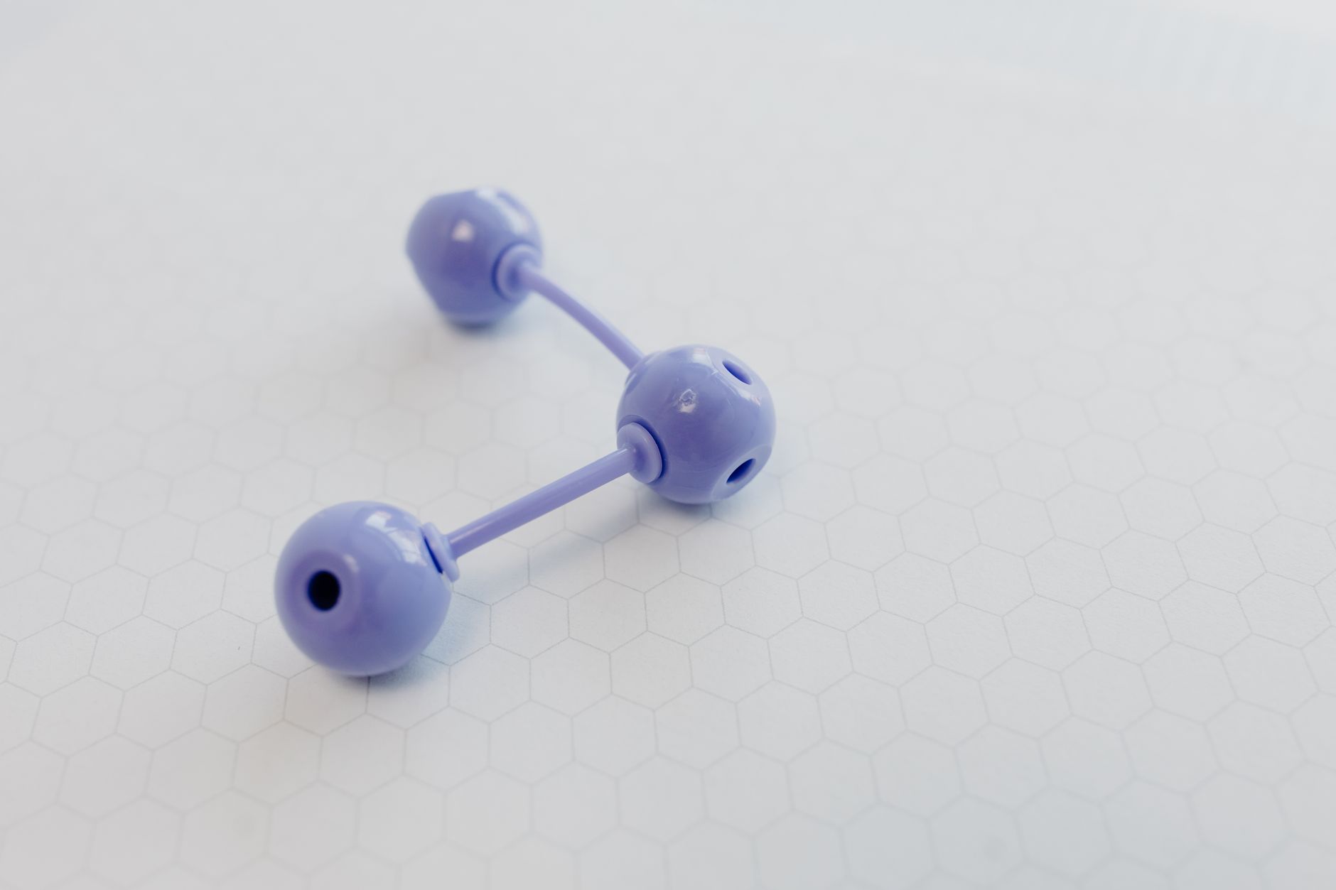 Einfaches Kugel-Stab-Modell aus drei violetten Atomen auf hellem Untergrund