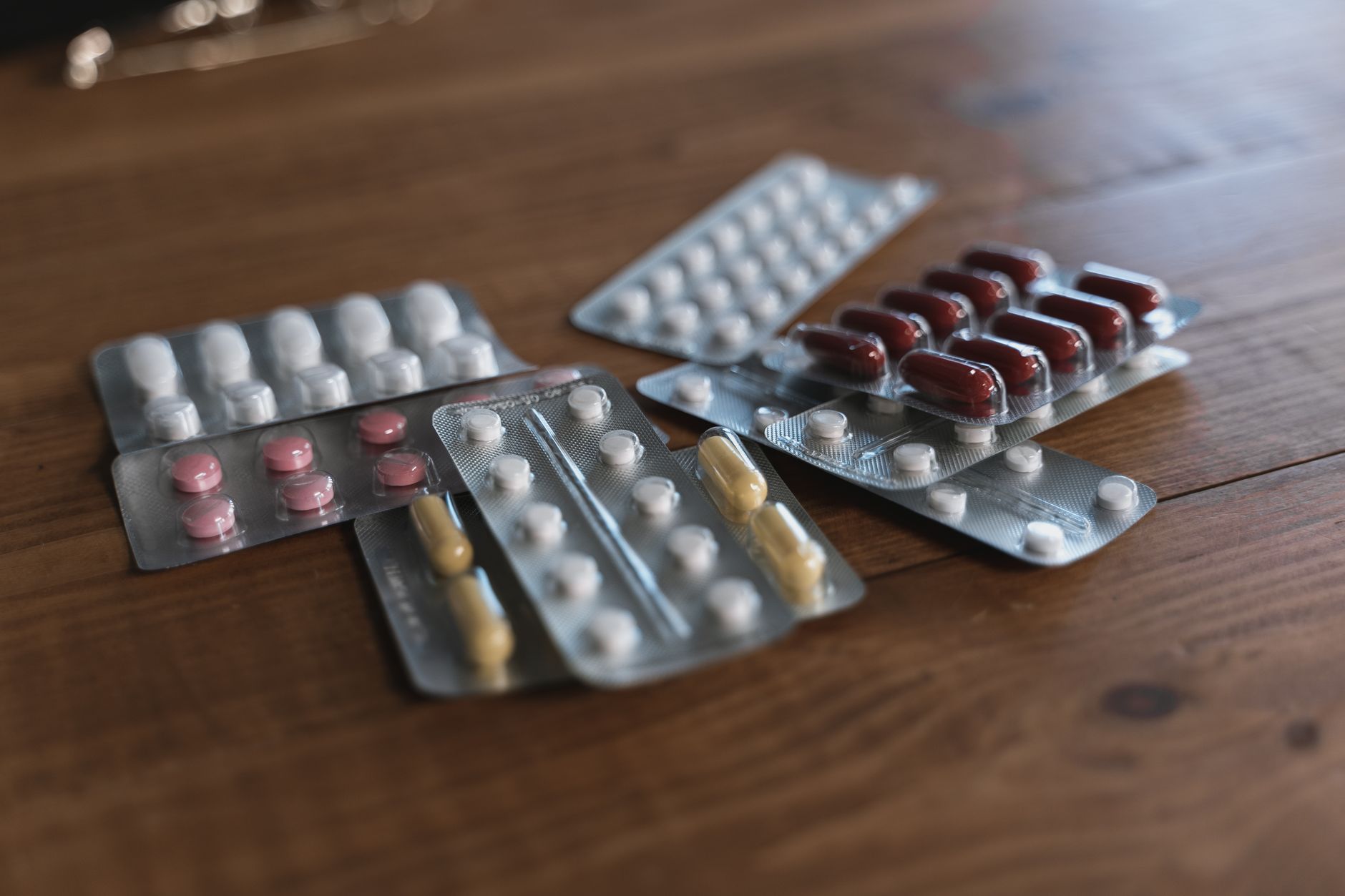 Verschiedene Tabletten und Kapseln in Blisterpackungen auf einem Holztisch