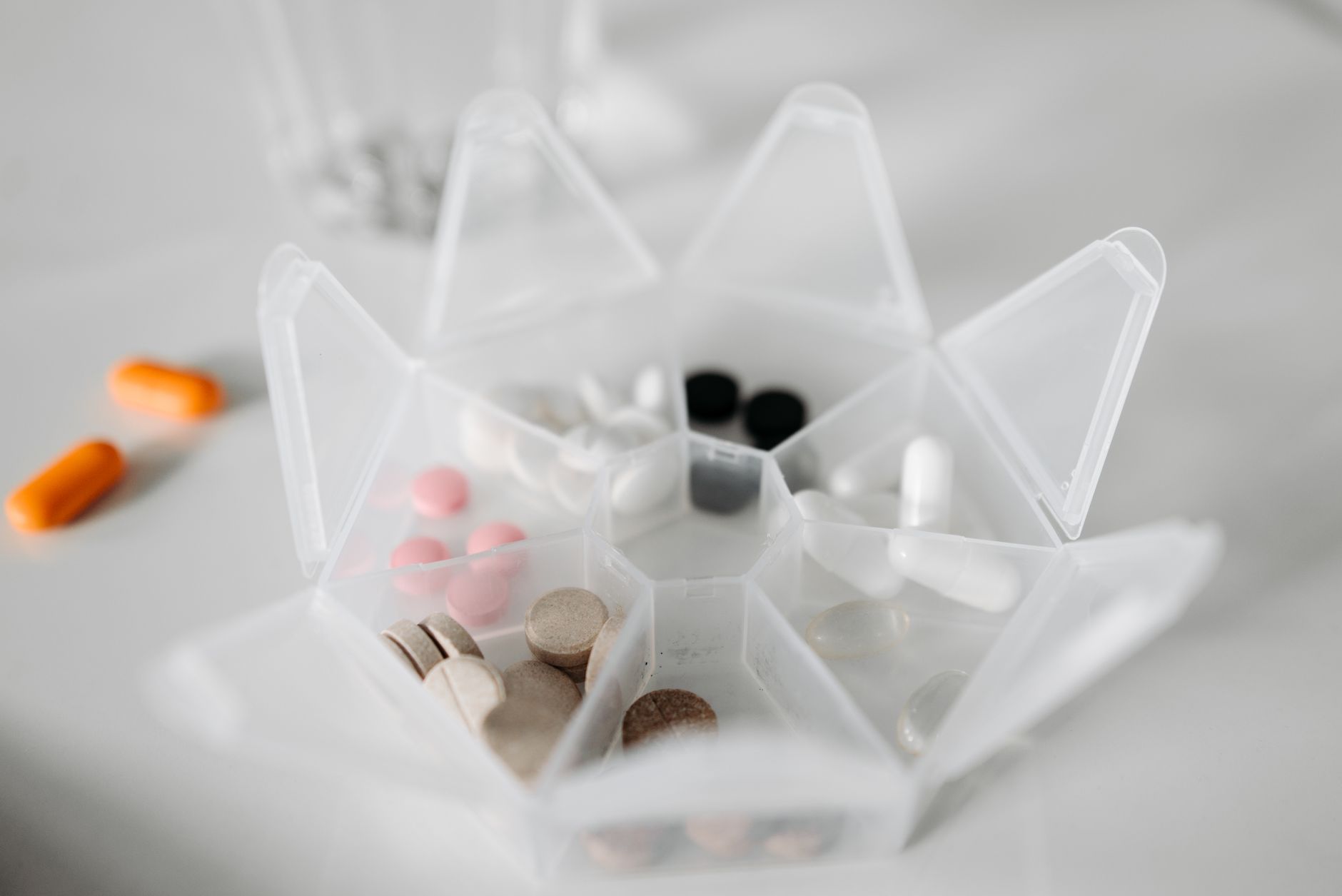 Wochendosierer aus durchsichtigem Kunststoff mit Tabletten und Kapseln in den einzelnen Fächern.