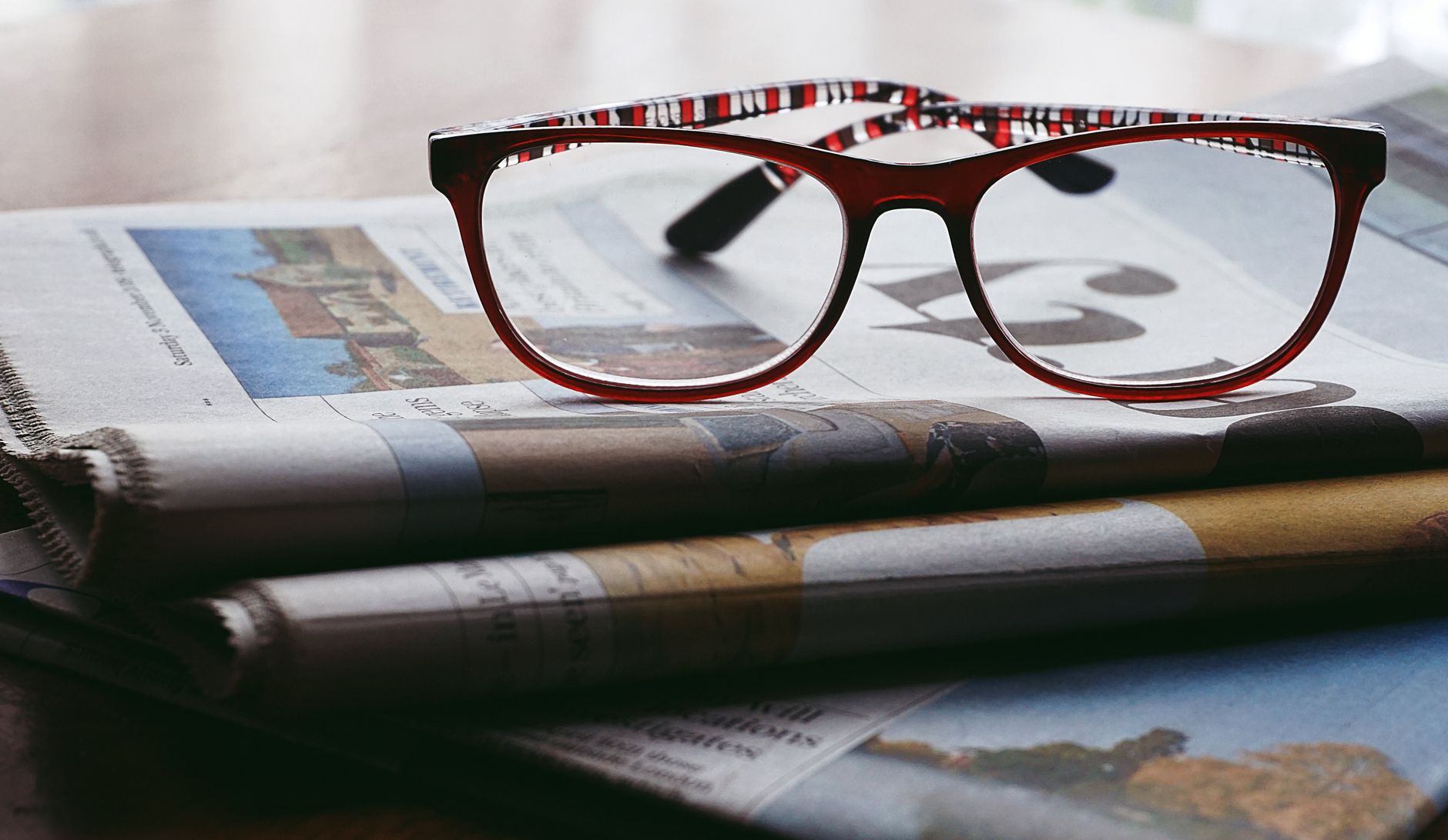 Reading glasses on a stack of folded newspapers