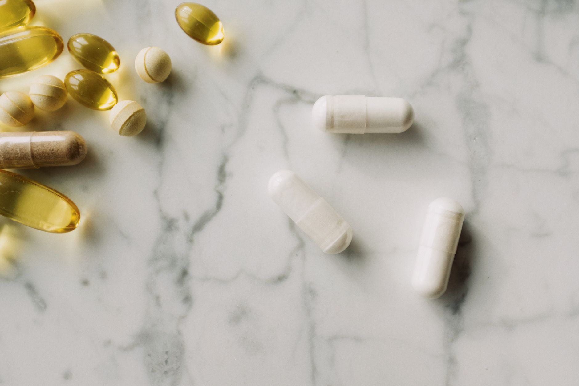 Tabletten, Hartkapseln und Softgel-Kapseln auf einer Marmorplatte