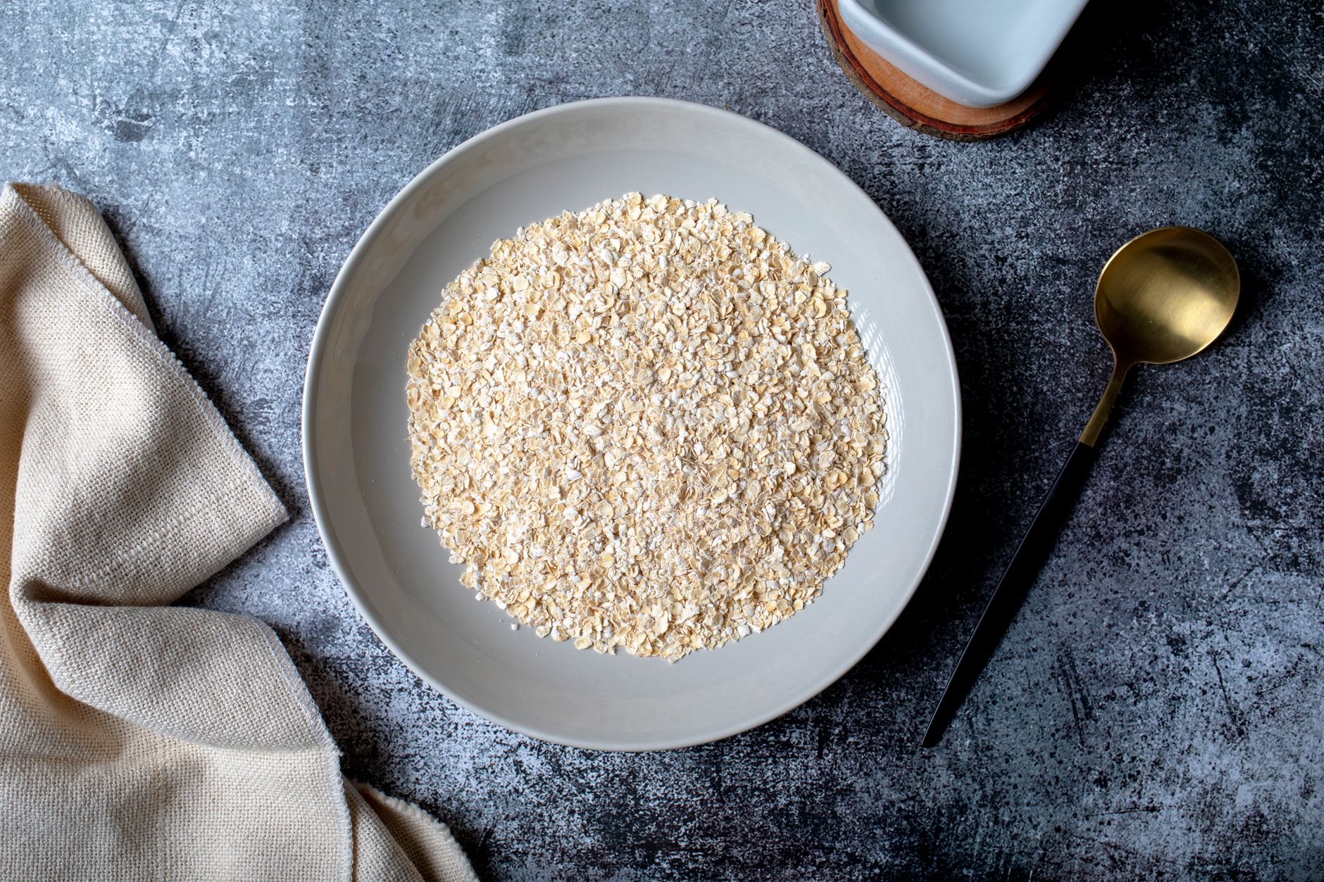 Eine Schale mit Haferflocken, daneben Löffel und Milchkännchen