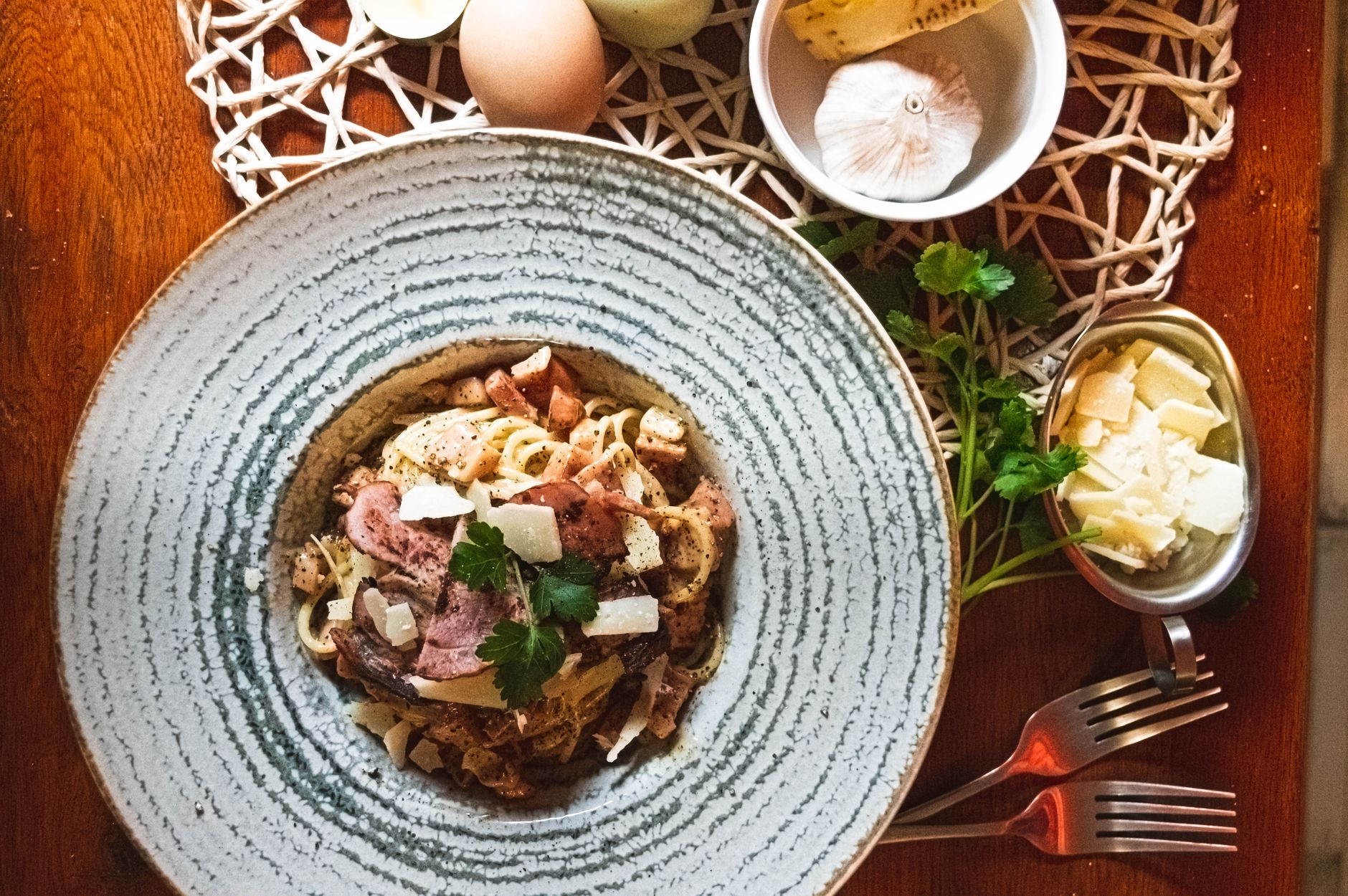 Piatto di pasta, accanto uova, aglio e formaggio grattugiato