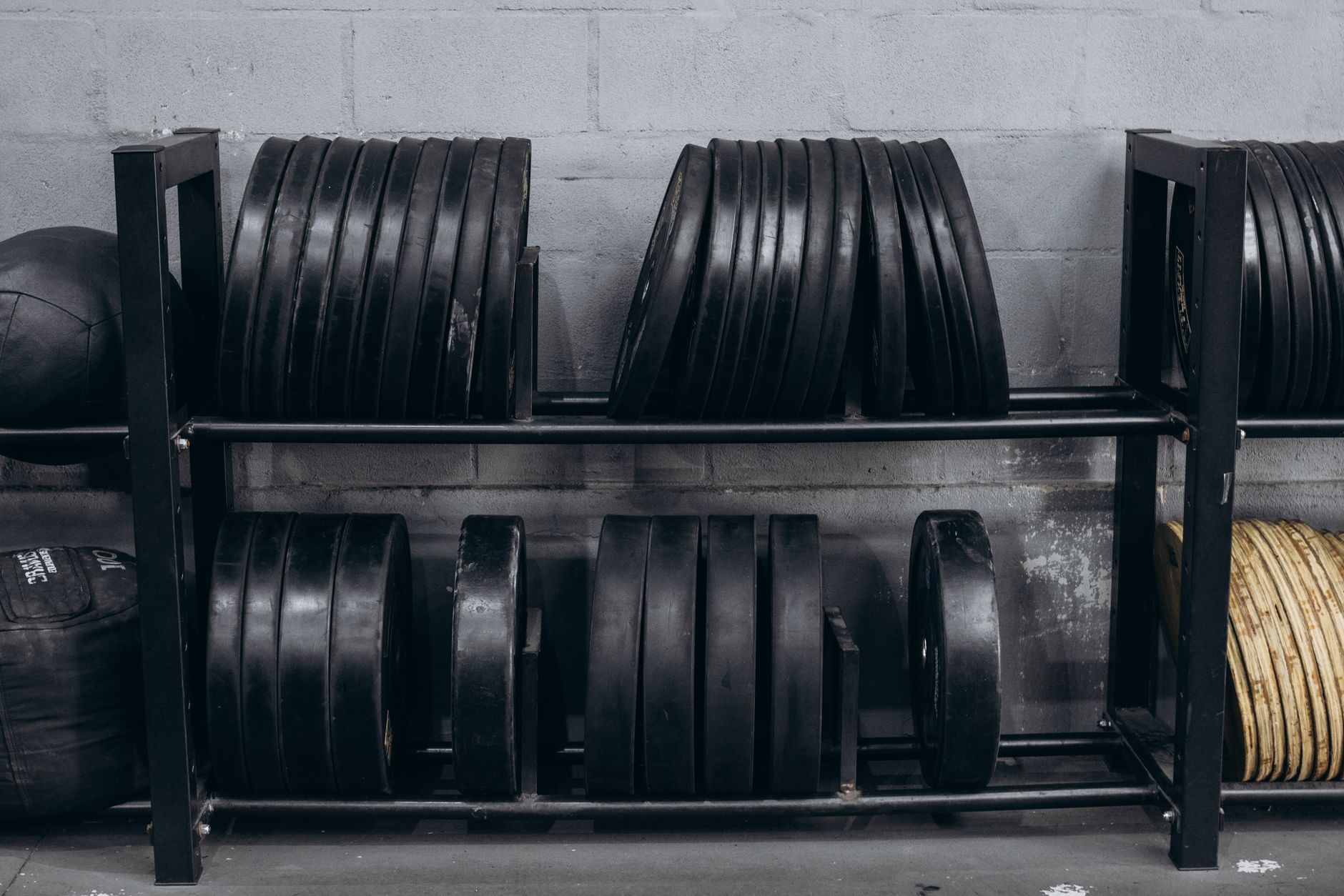 Weight plates in a rack against a concrete wall