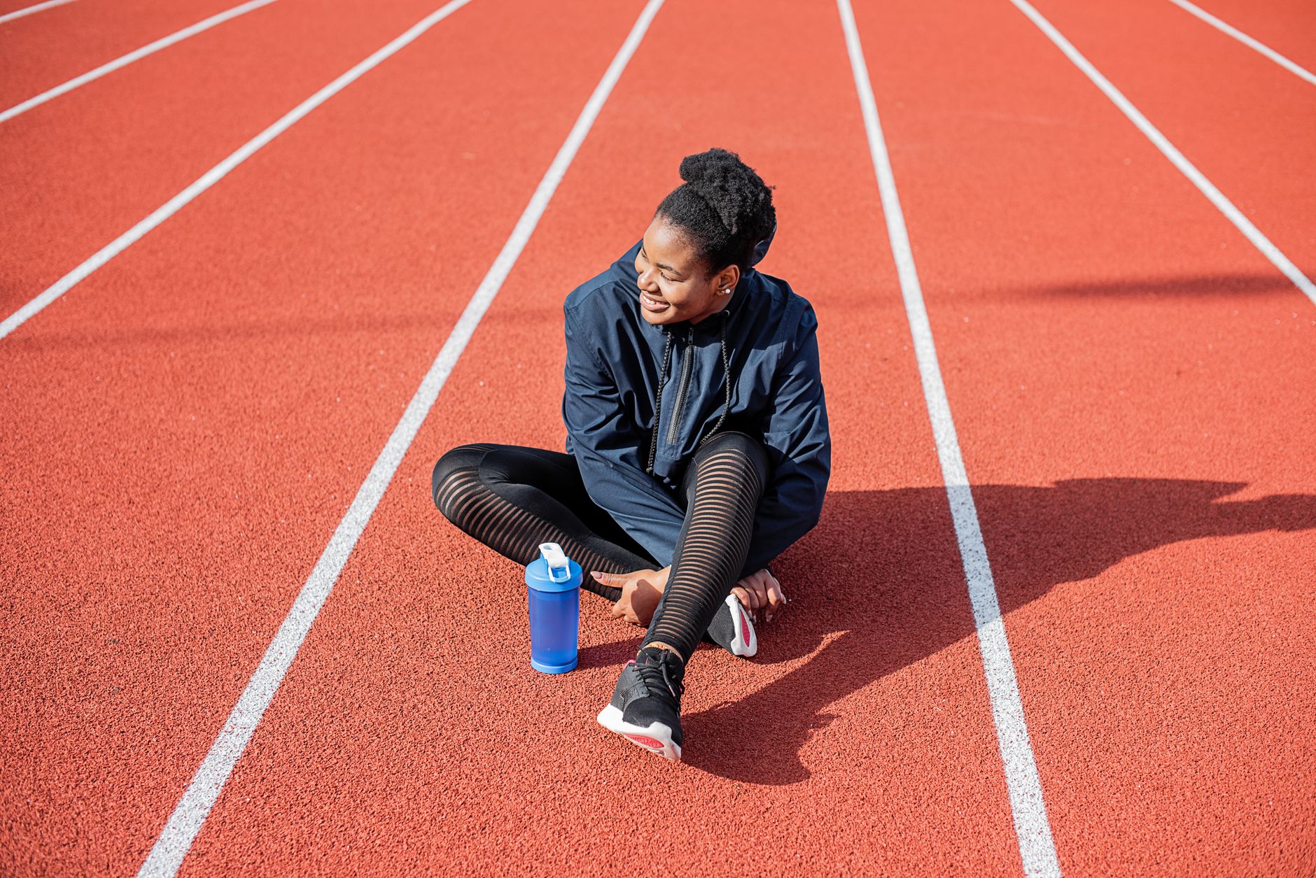 Runner sitting on a running track with a water bottle