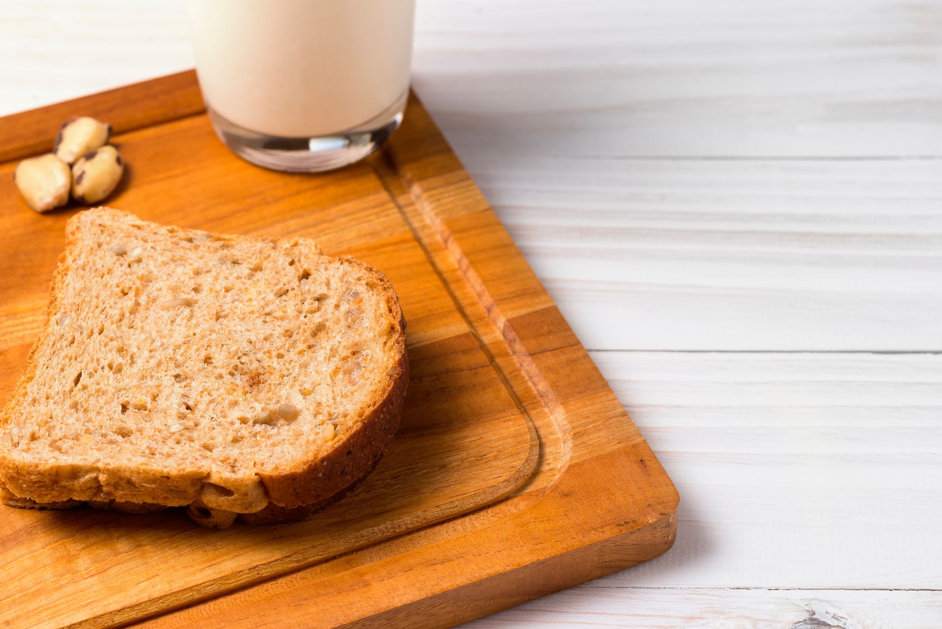 Vollkornbrot und ein Glas Milch auf einem Holzbrett