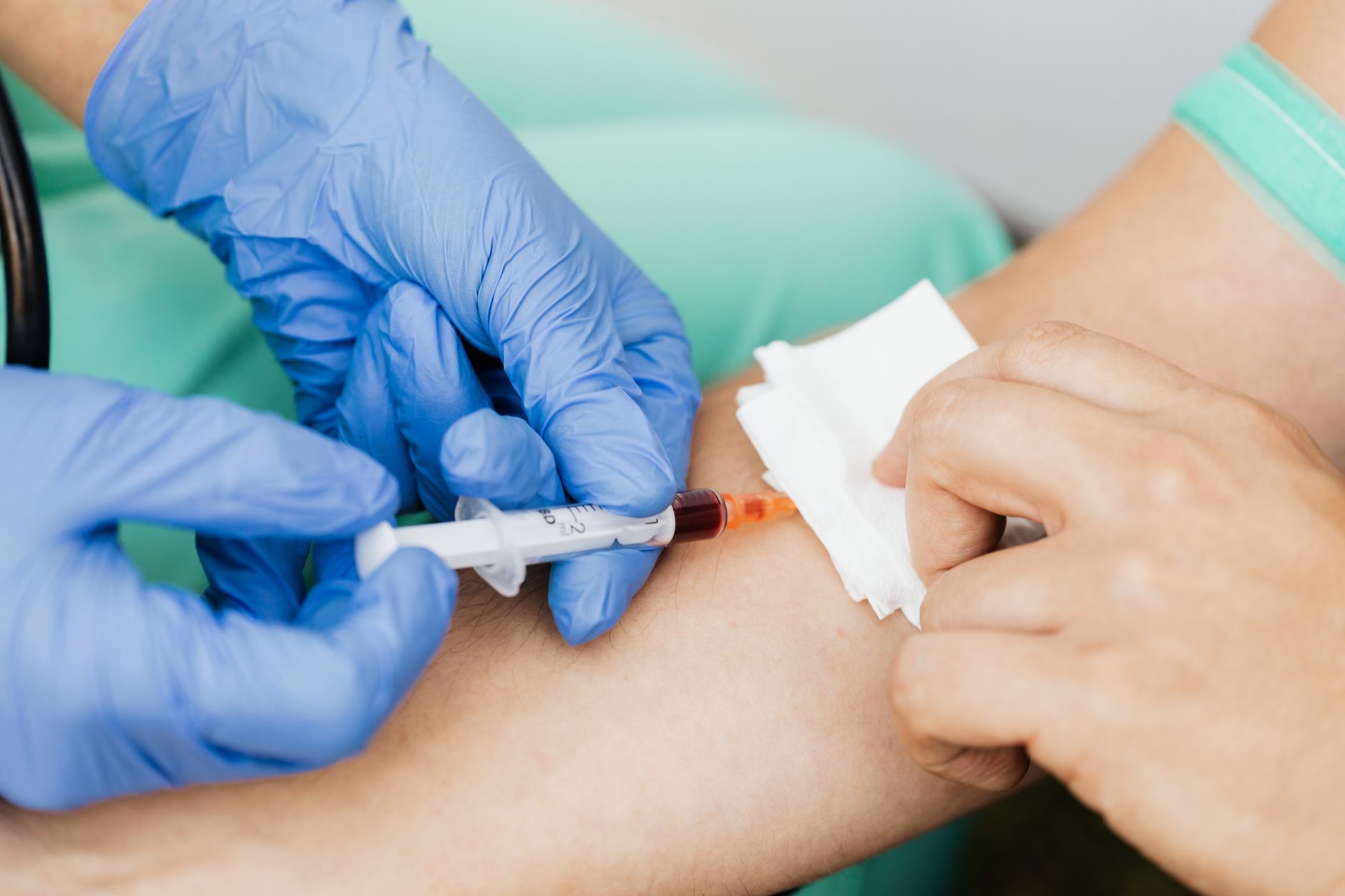 Prelievo di sangue dal braccio, mani con guanti blu guidano la siringa