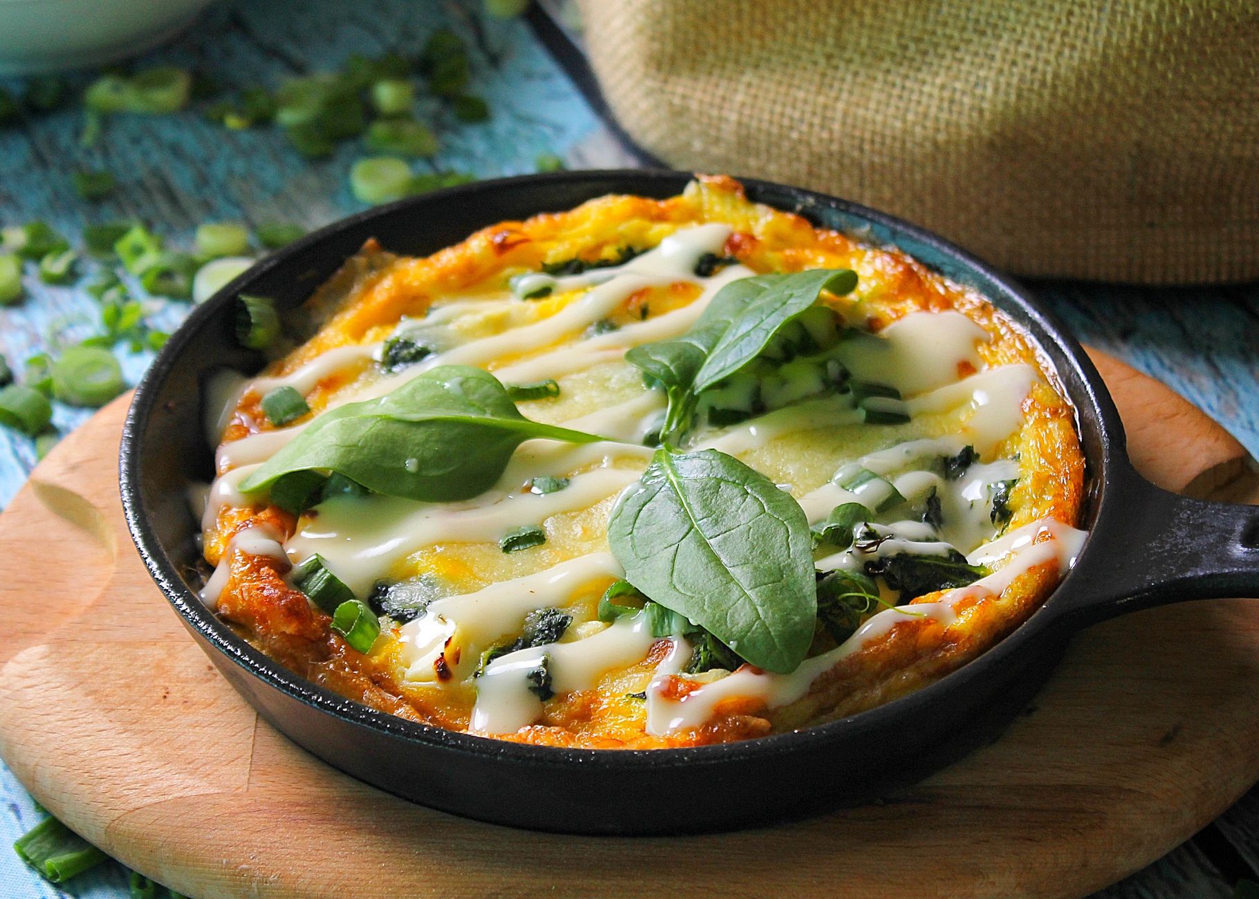 Frittata mit Spinat, Frühlingszwiebeln und Käse in einer gusseisernen Pfanne