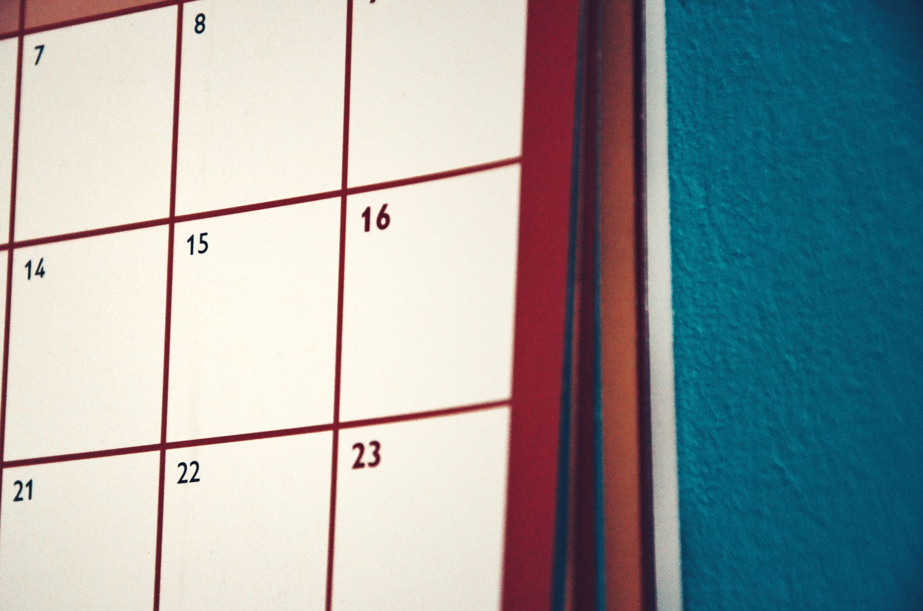 Wandkalender mit leeren Tagesfeldern vor einer türkisfarbenen Wand