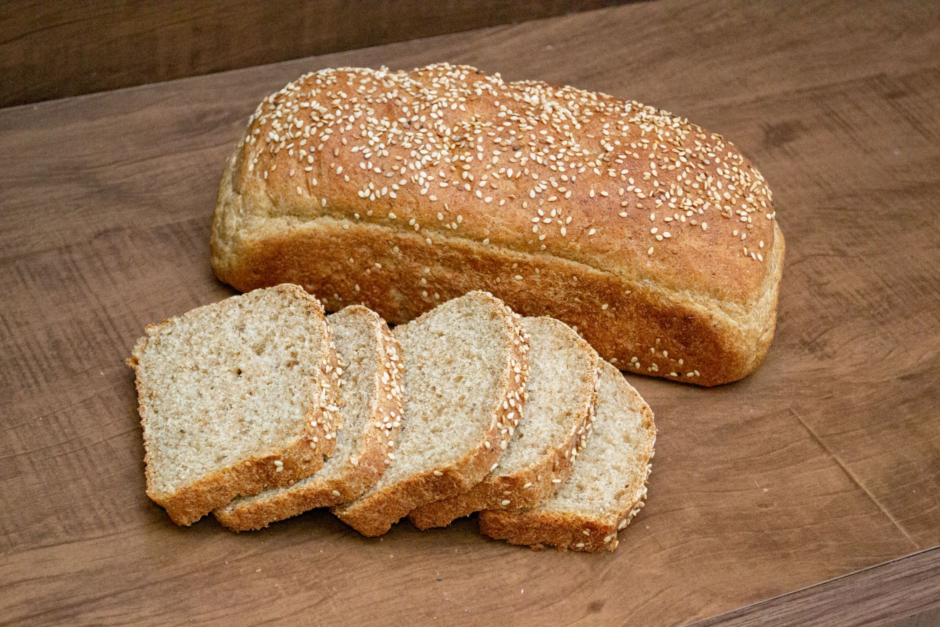 Ein aufgeschnittener Brotlaib mit Sesam auf einem Holzbrett