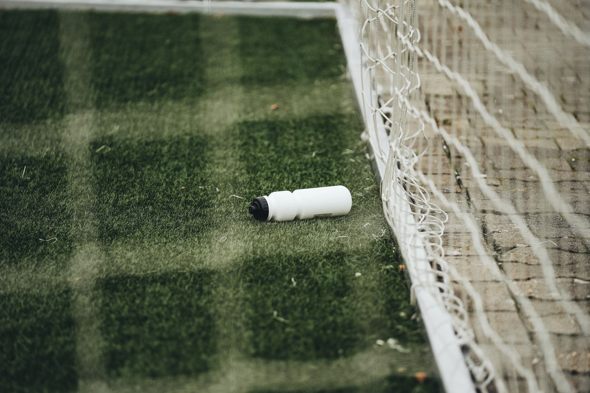 A white water bottle in the grass beside a football goal