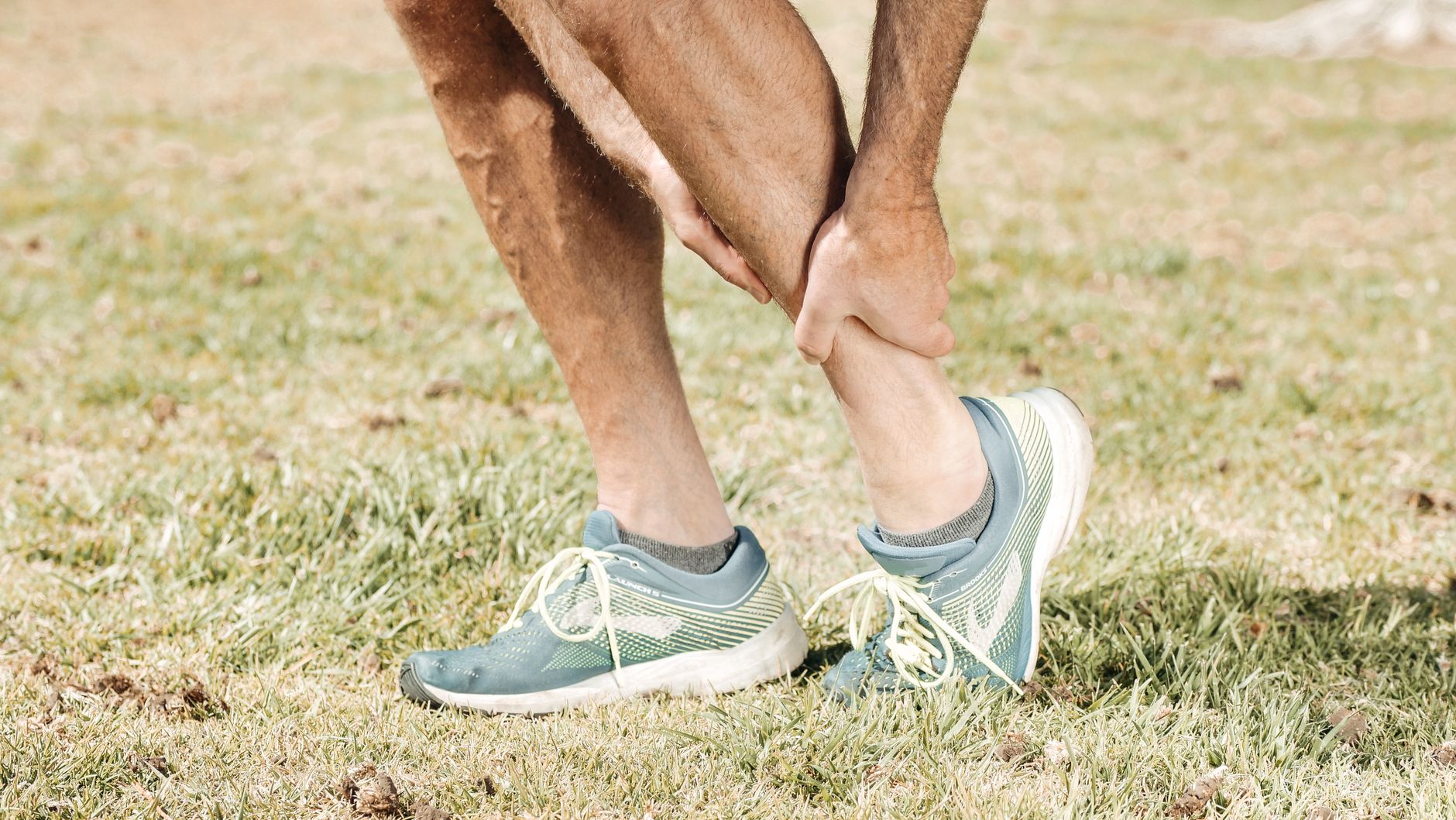 A runner standing, holding their calf