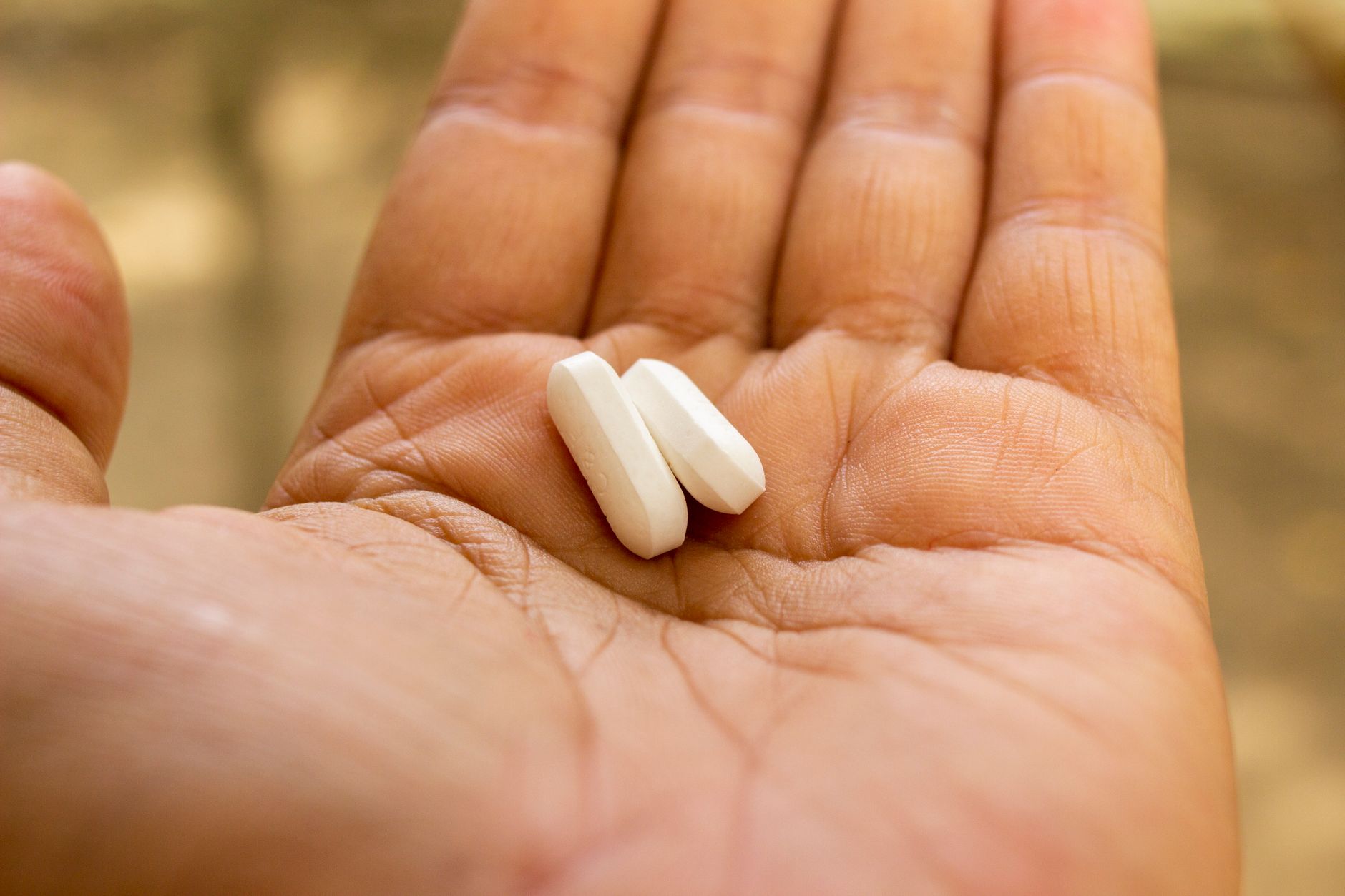 Due compresse bianche nel palmo di una mano aperta