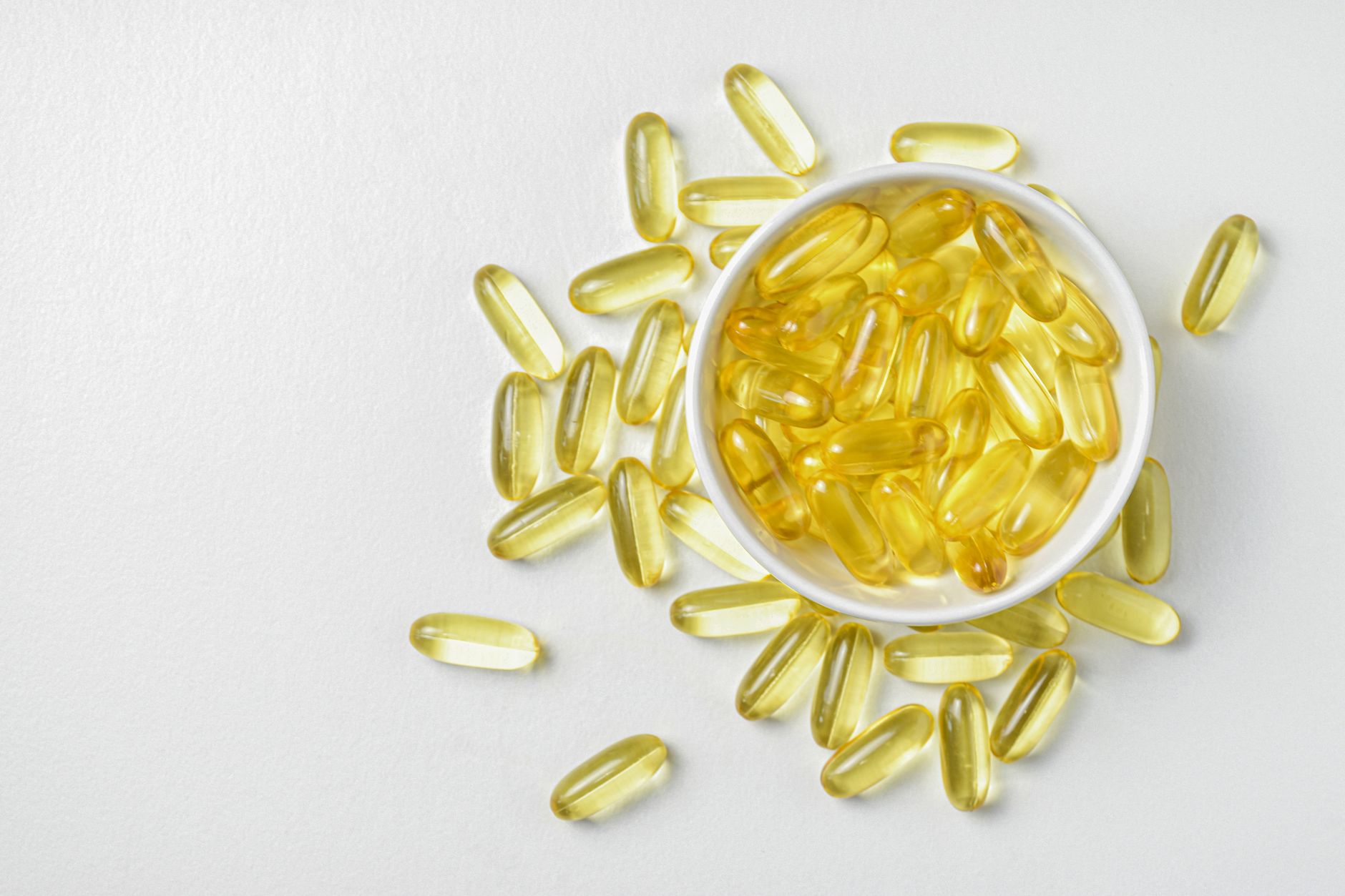 Capsule di vitamina D in una ciotolina bianca – la forma liposolubile si assume di norma durante un pasto