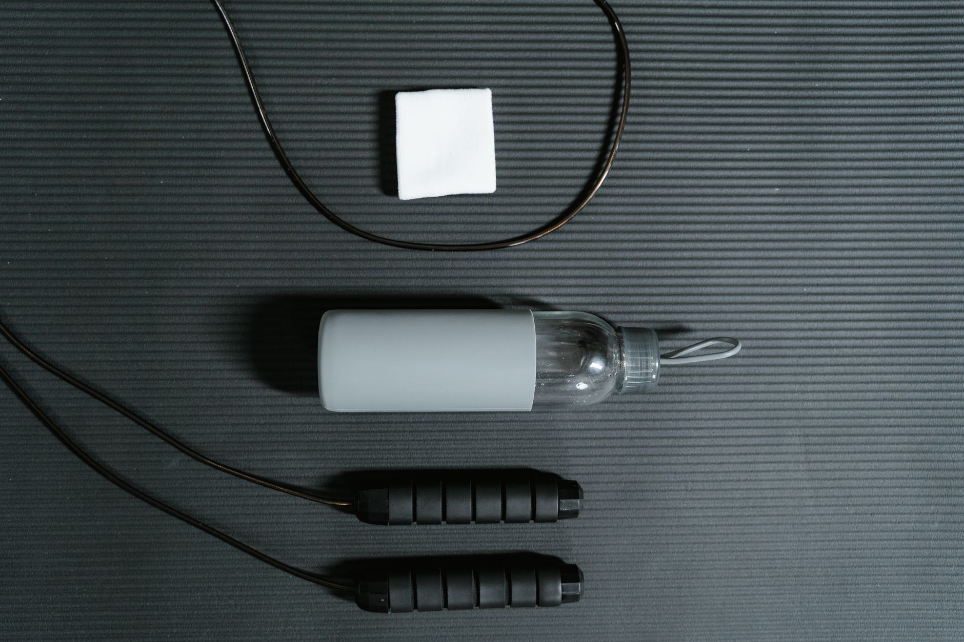 Skipping rope, water bottle and towel on a mat