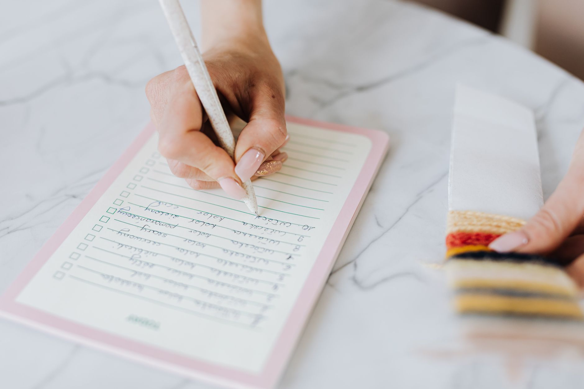 Eine Hand schreibt eine Checkliste auf liniertes Papier