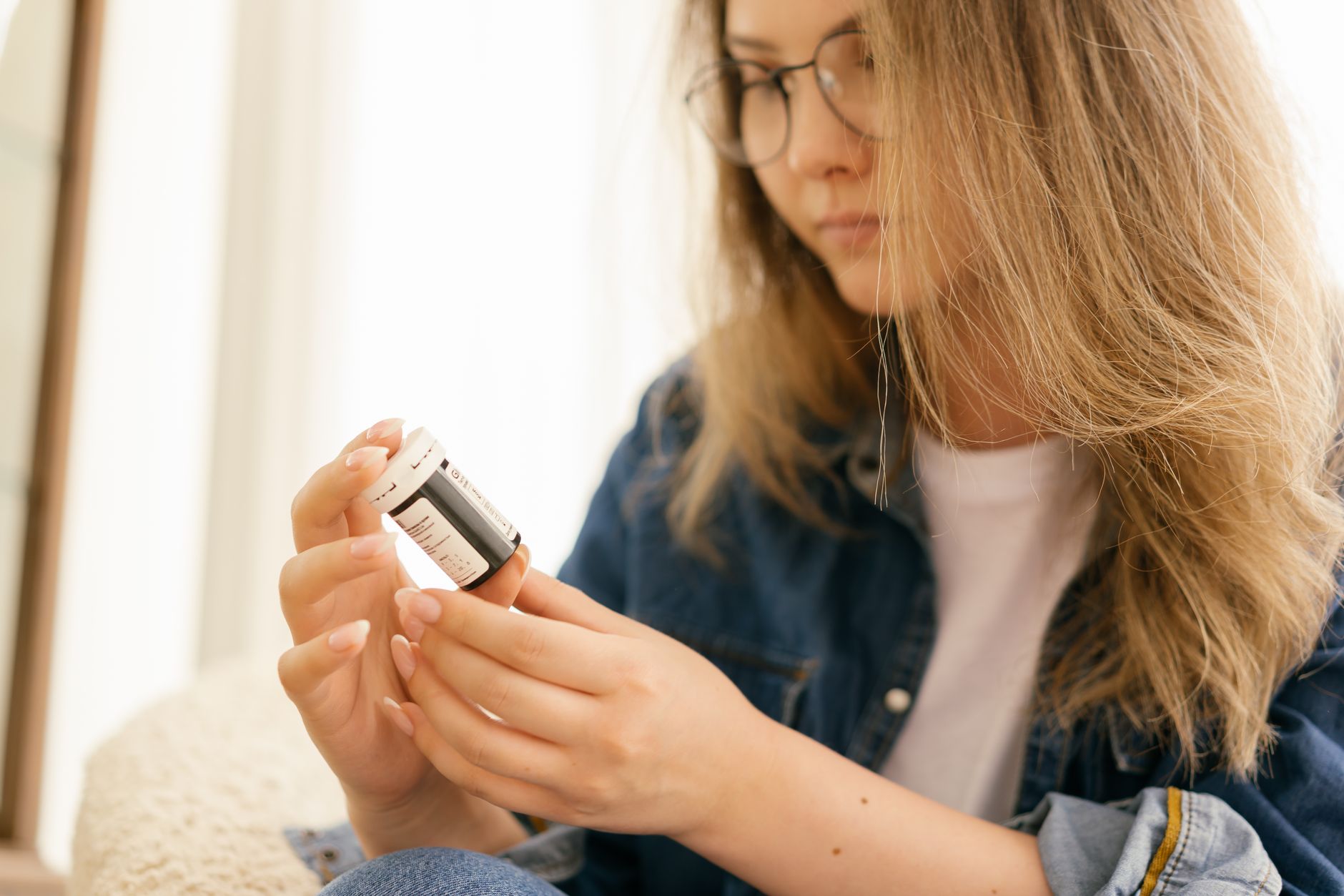 Frau liest die Rückseite einer Dose mit Tabletten