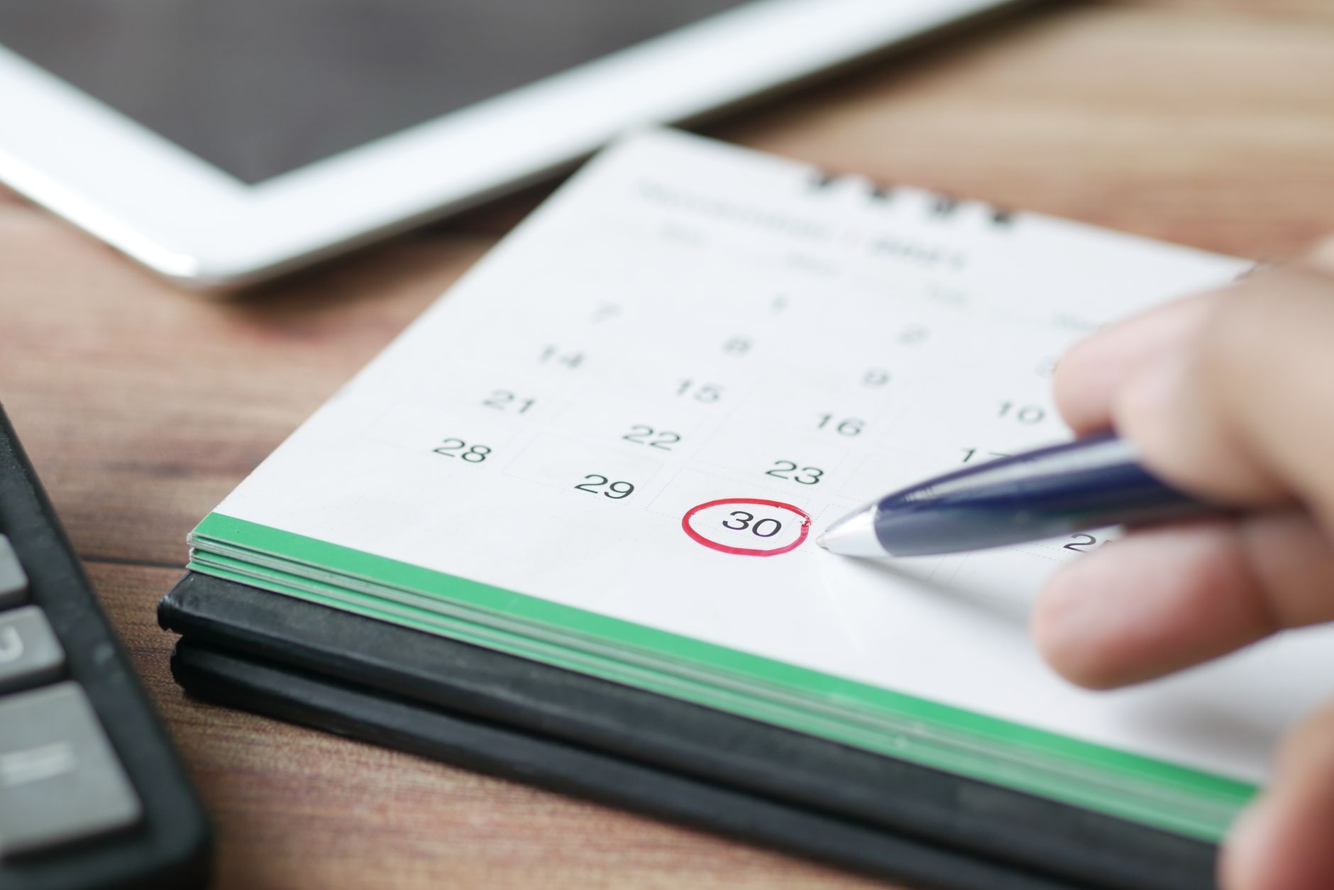 Hand markiert einen Termin in einem Kalender