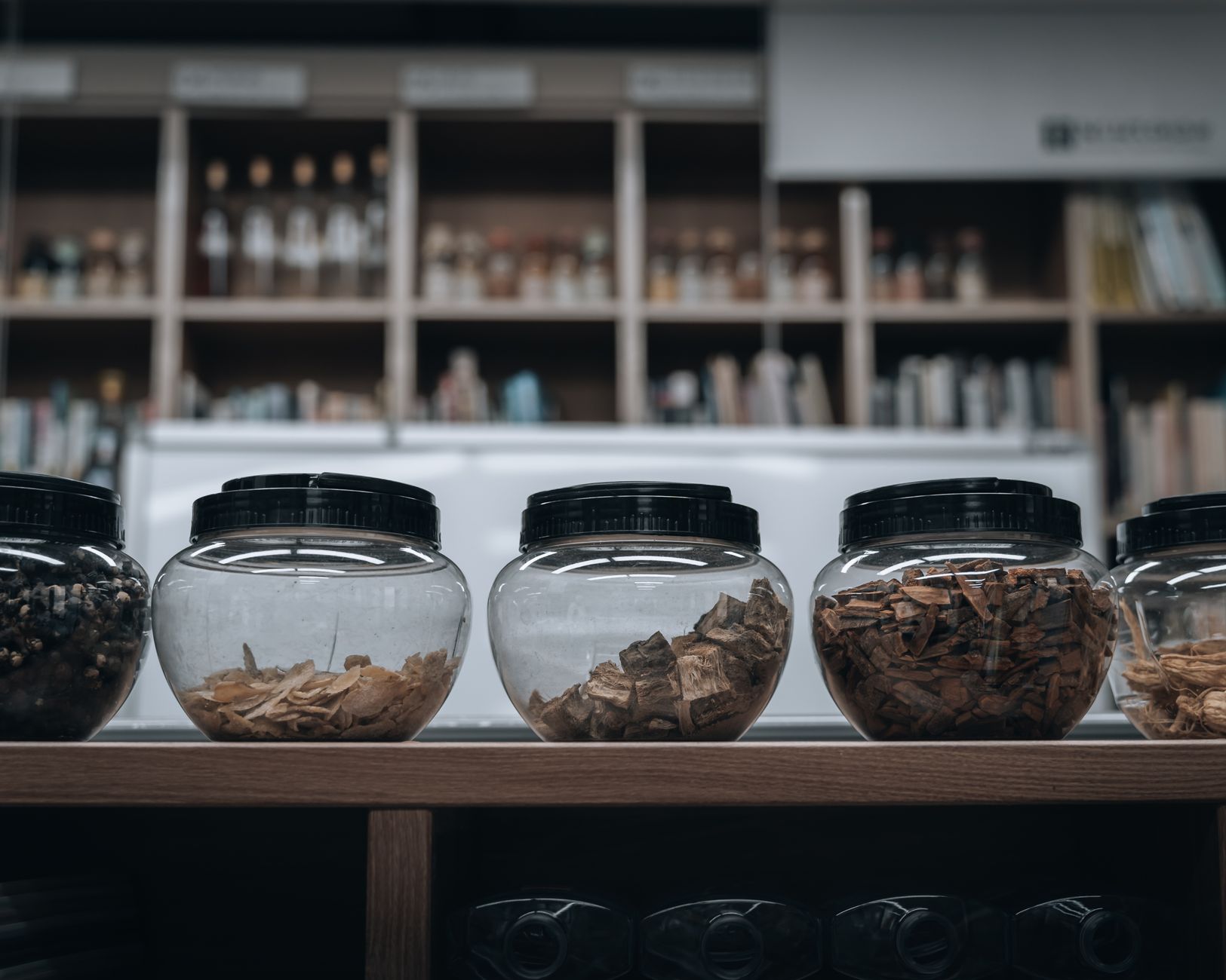 Vorratsgläser mit getrockneten Wurzelscheiben und Rinde in einer traditionellen Kräuterapotheke