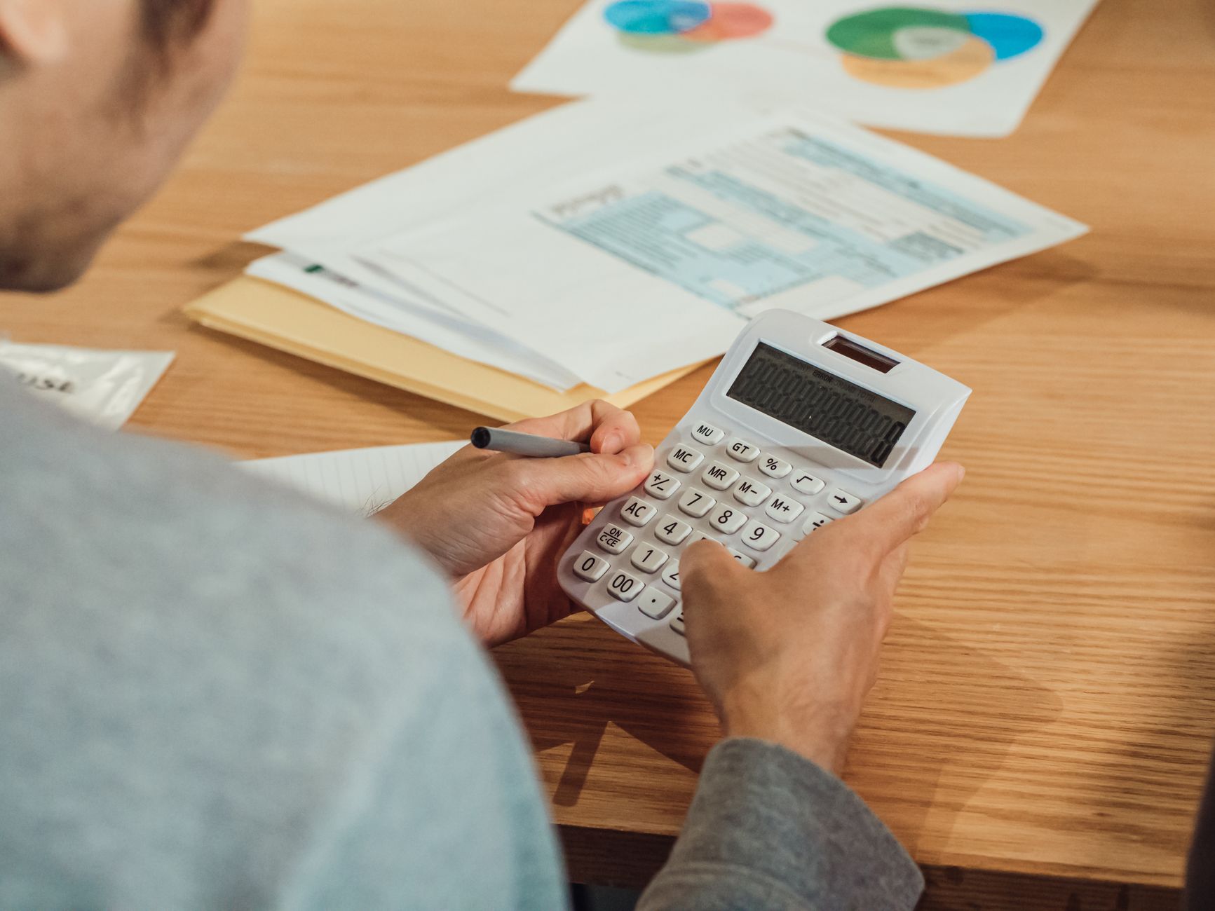 Person doing calculations with a calculator and paperwork at a desk
