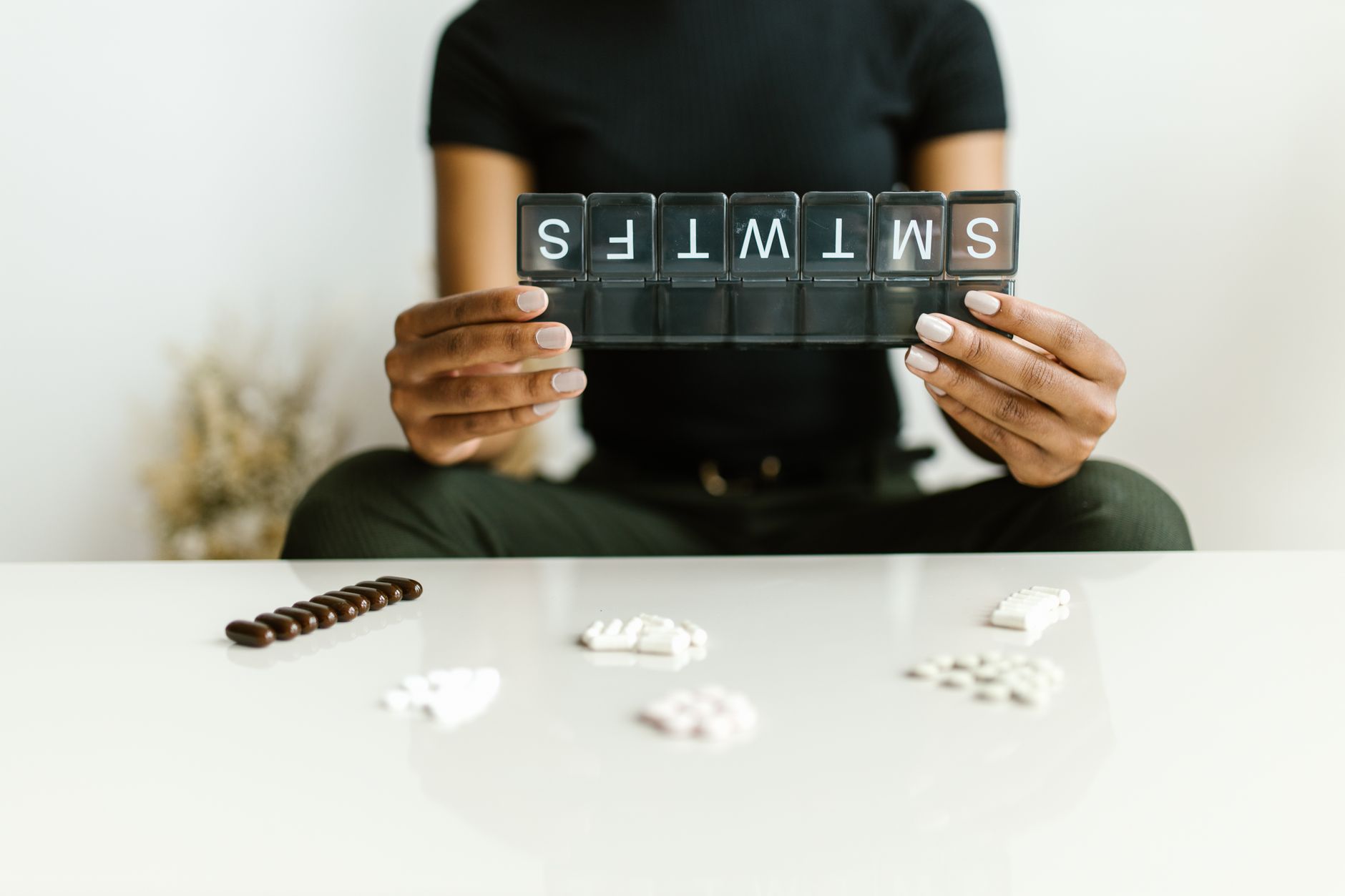 Person sorting tablets into a weekly pill organiser