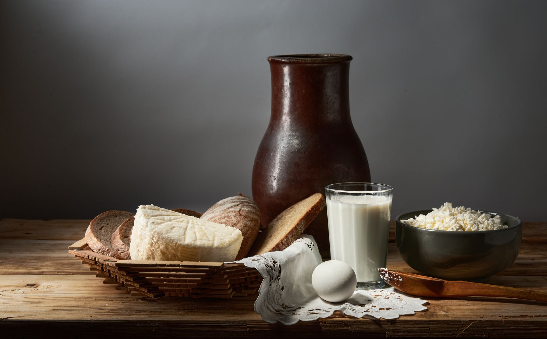 Rustikales Stillleben mit Brot, Käse, Ei und Milch auf Holz