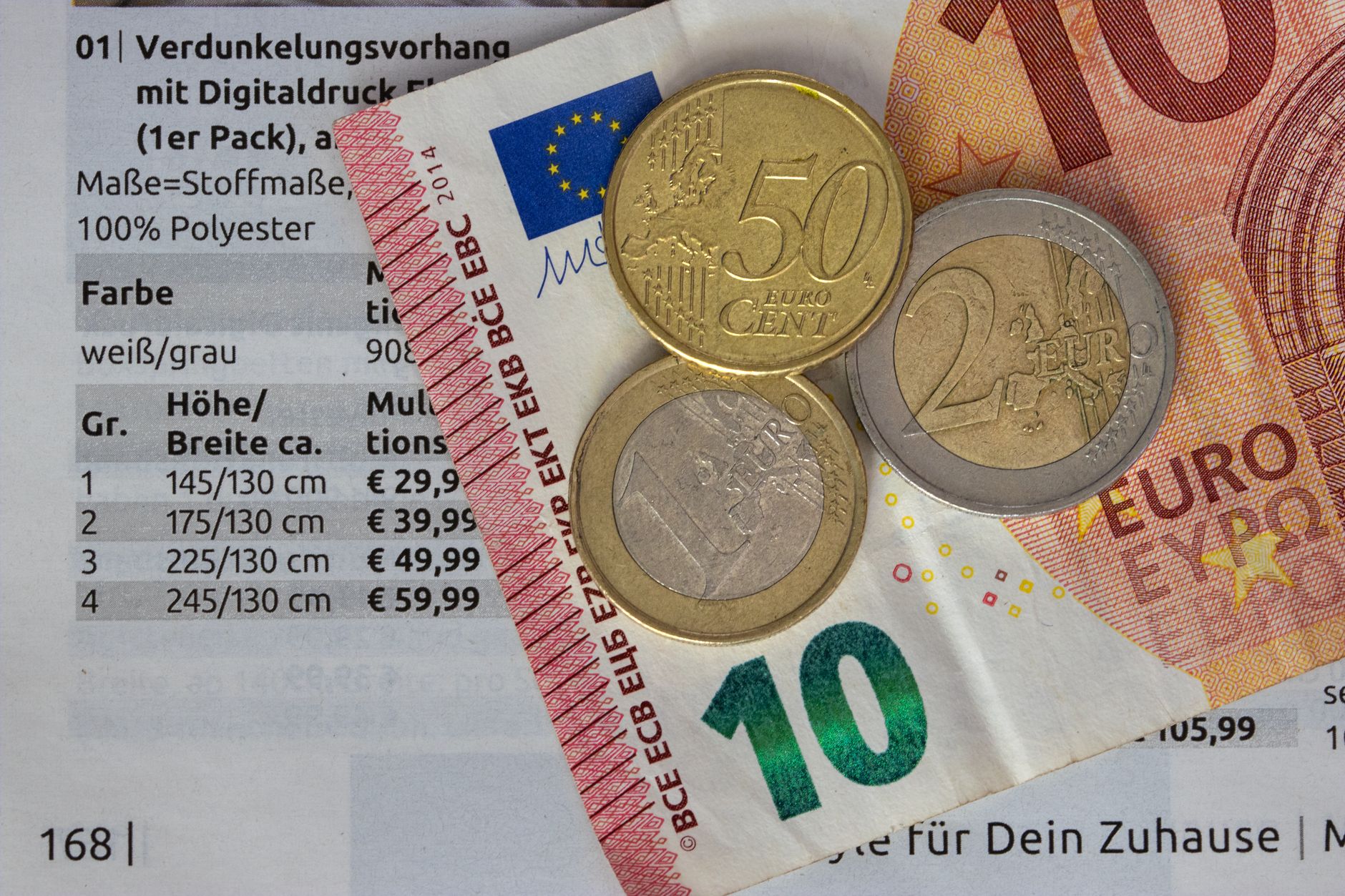 Monete in euro e una banconota da dieci euro su un listino prezzi.