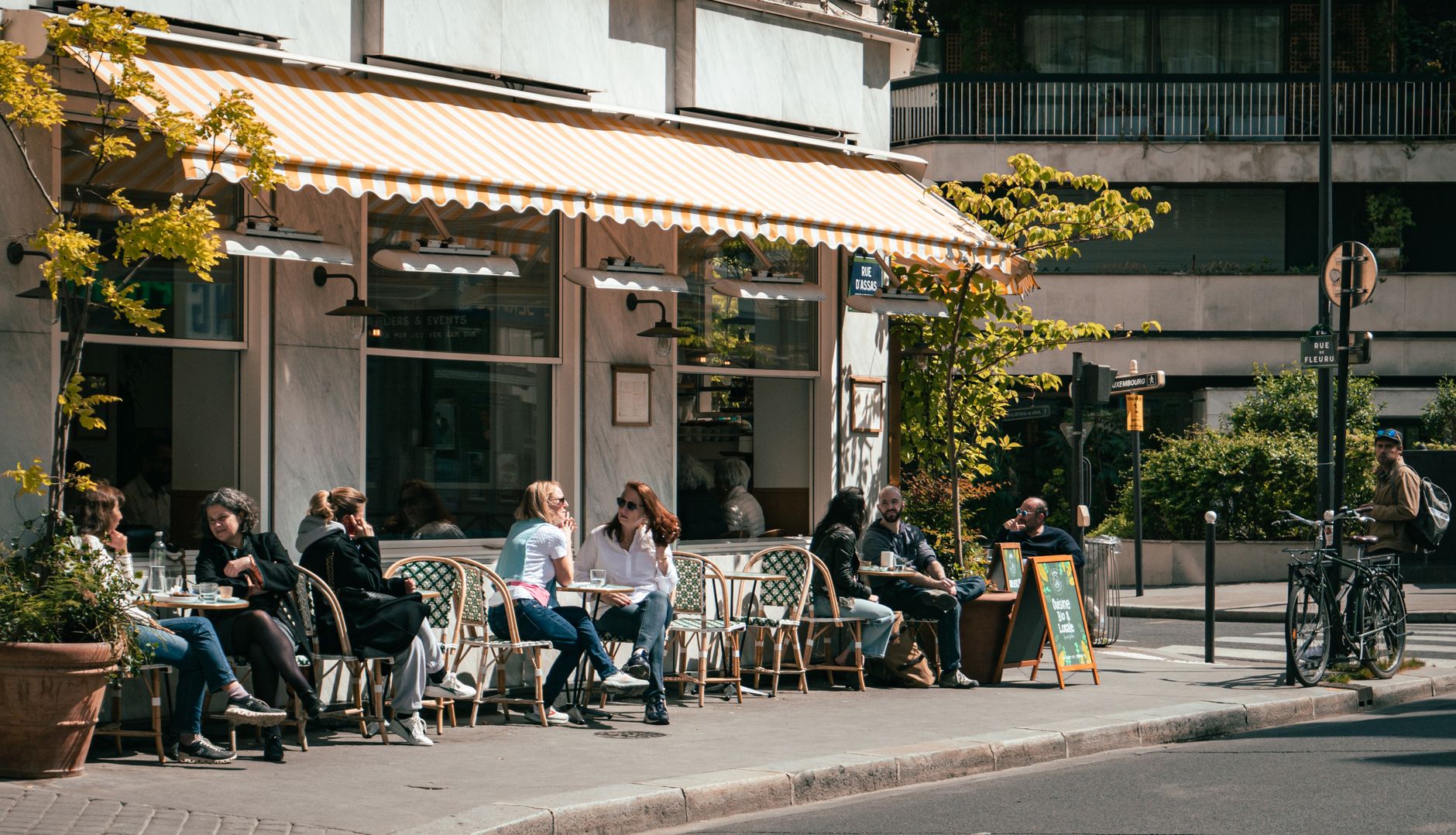 Clienti seduti davanti a un caffè all'aperto in un pomeriggio di sole.