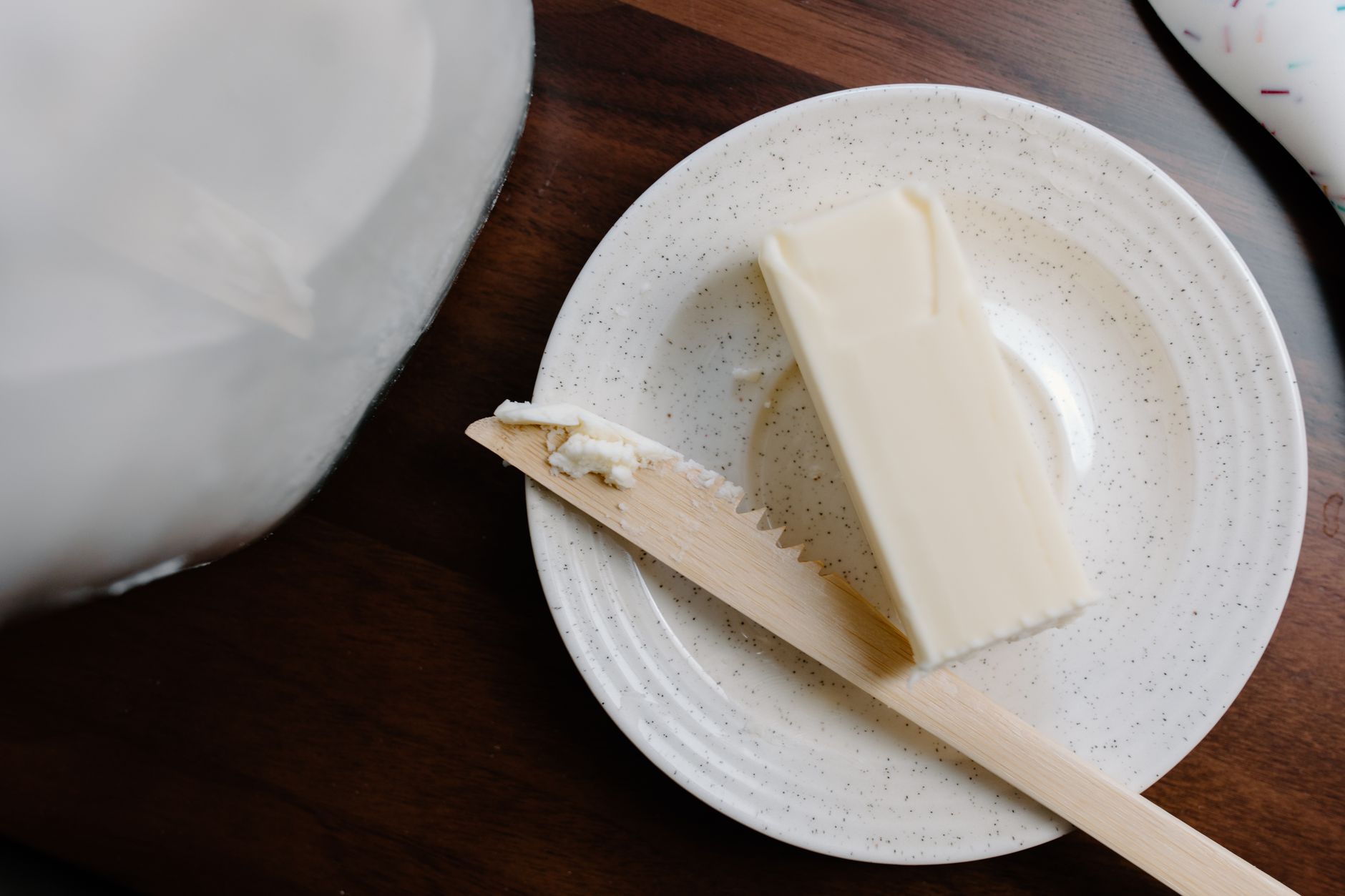 Ein Stück Butter mit Holzmesser auf einem rustikalen Teller.