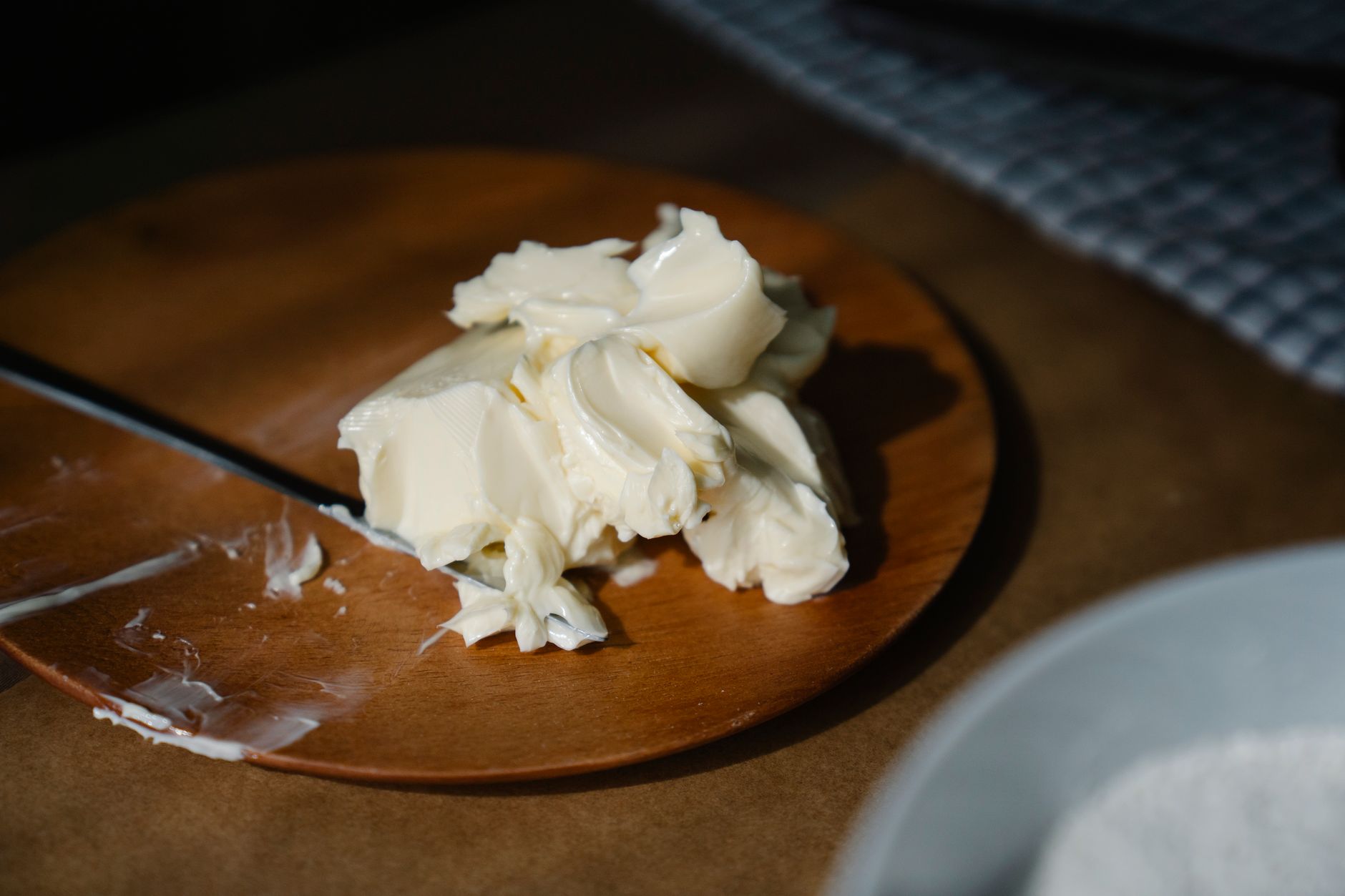 Cremiges Streichfett auf einem Holzteller, daneben ein Messer.