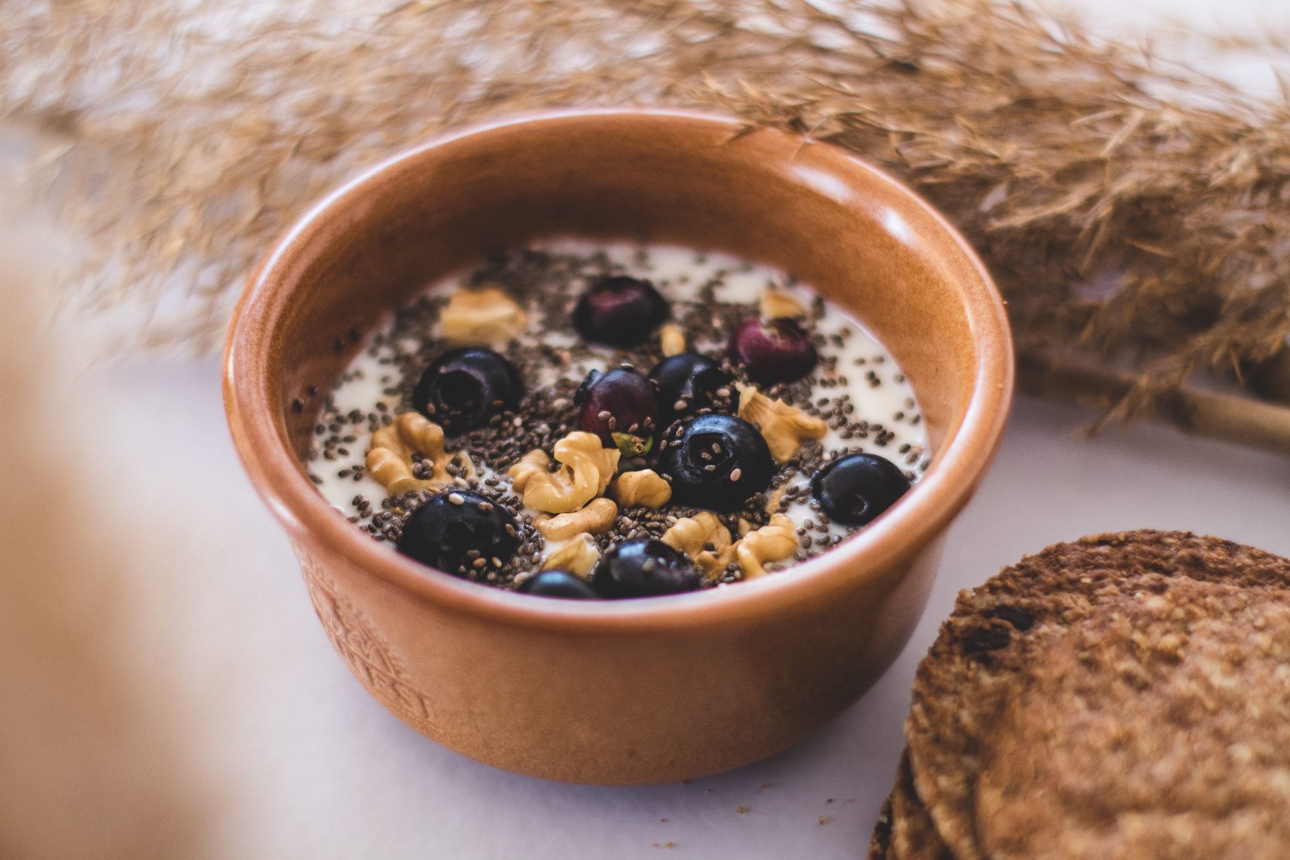 Schale mit Joghurt, Blaubeeren, Walnüssen und Chiasamen auf einem hellen Tisch