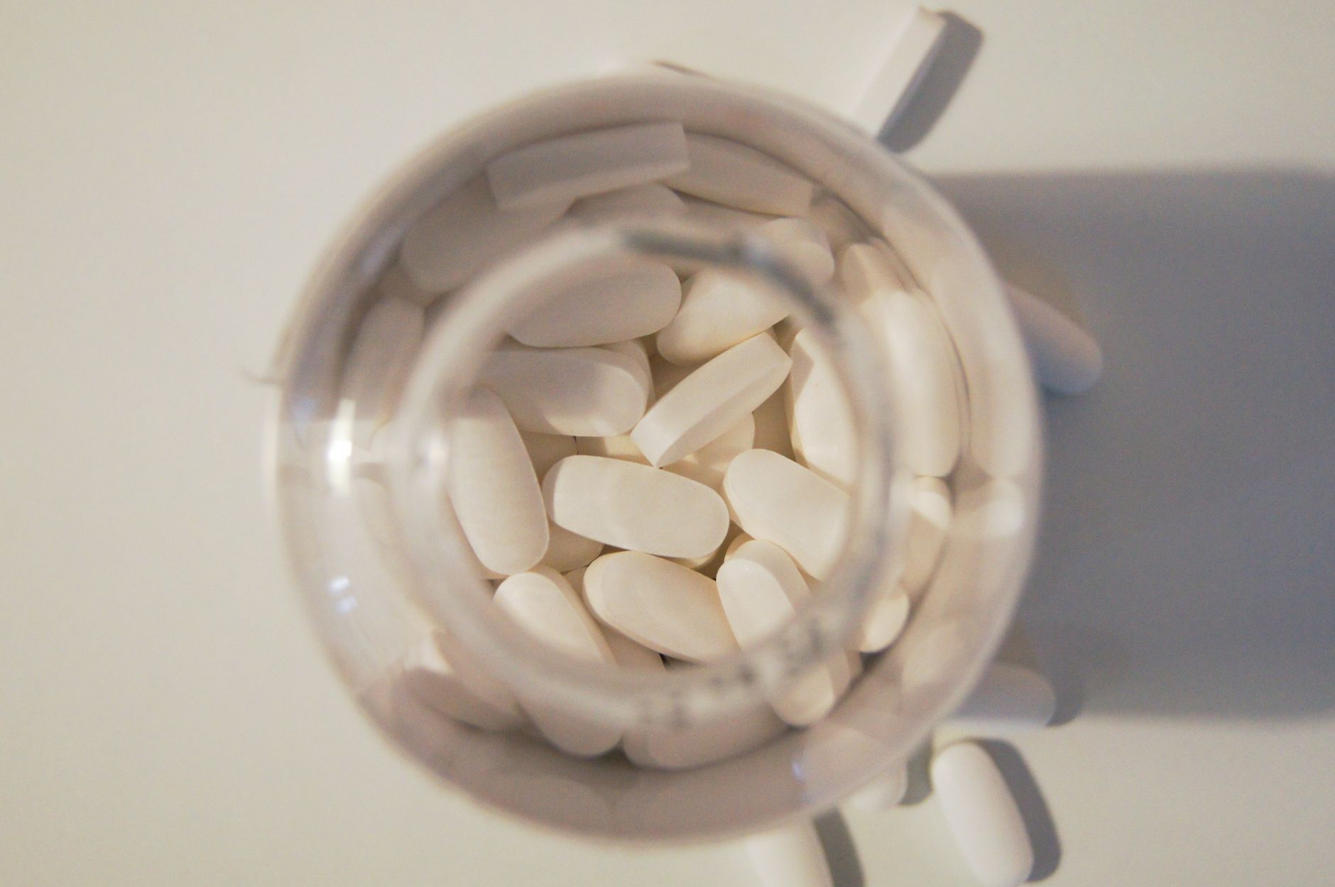 Weiße Tabletten in einem gläsernen Vorratsgefäß von oben fotografiert