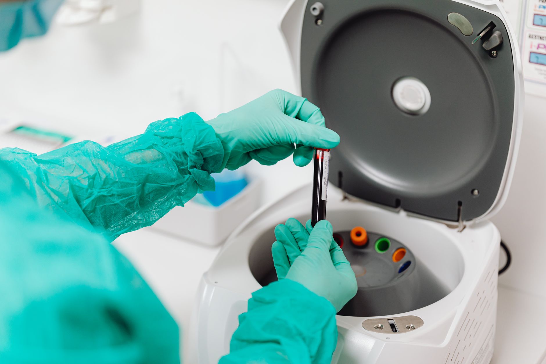 Laborkraft stellt ein Blutröhrchen in eine Zentrifuge