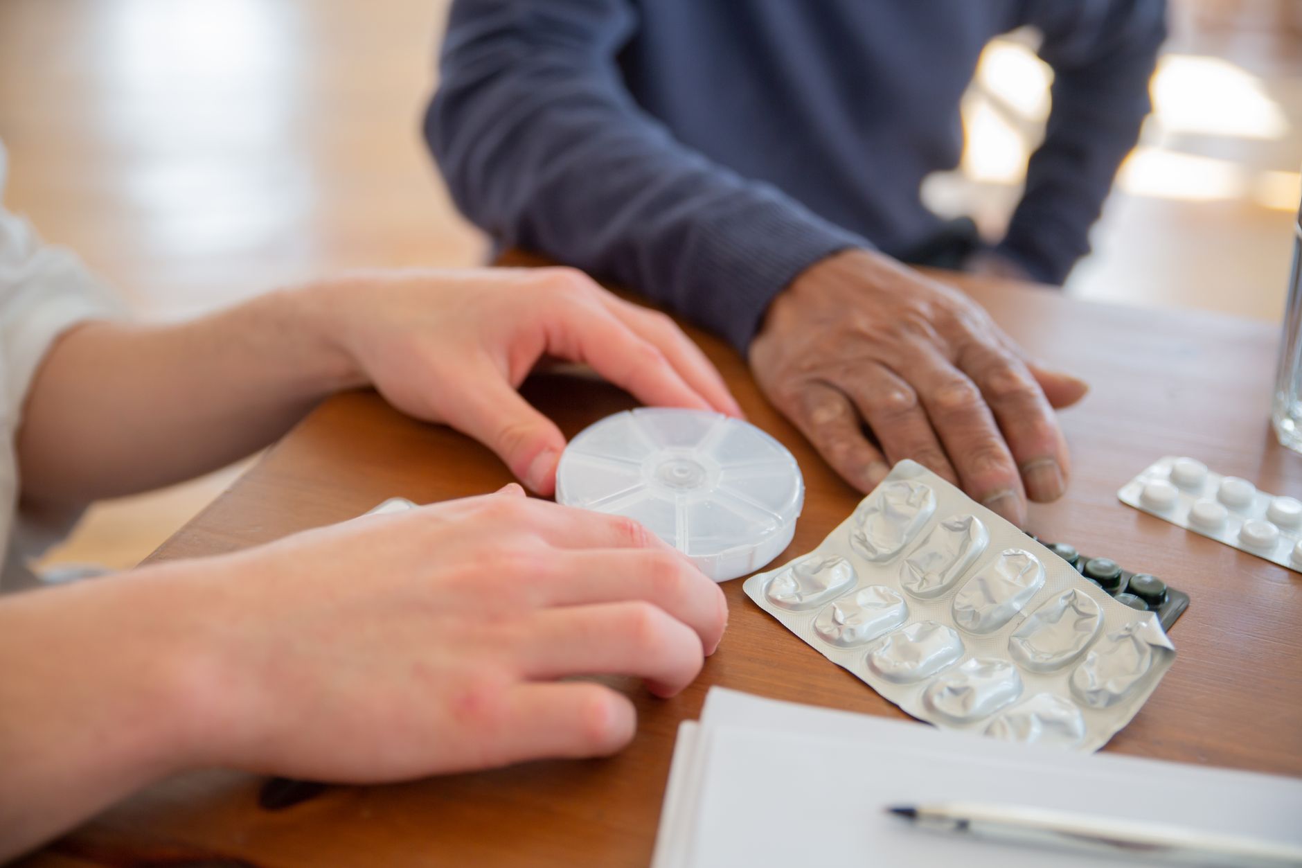 Zwei Personen sortieren Tabletten und Blisterpackungen an einem Tisch