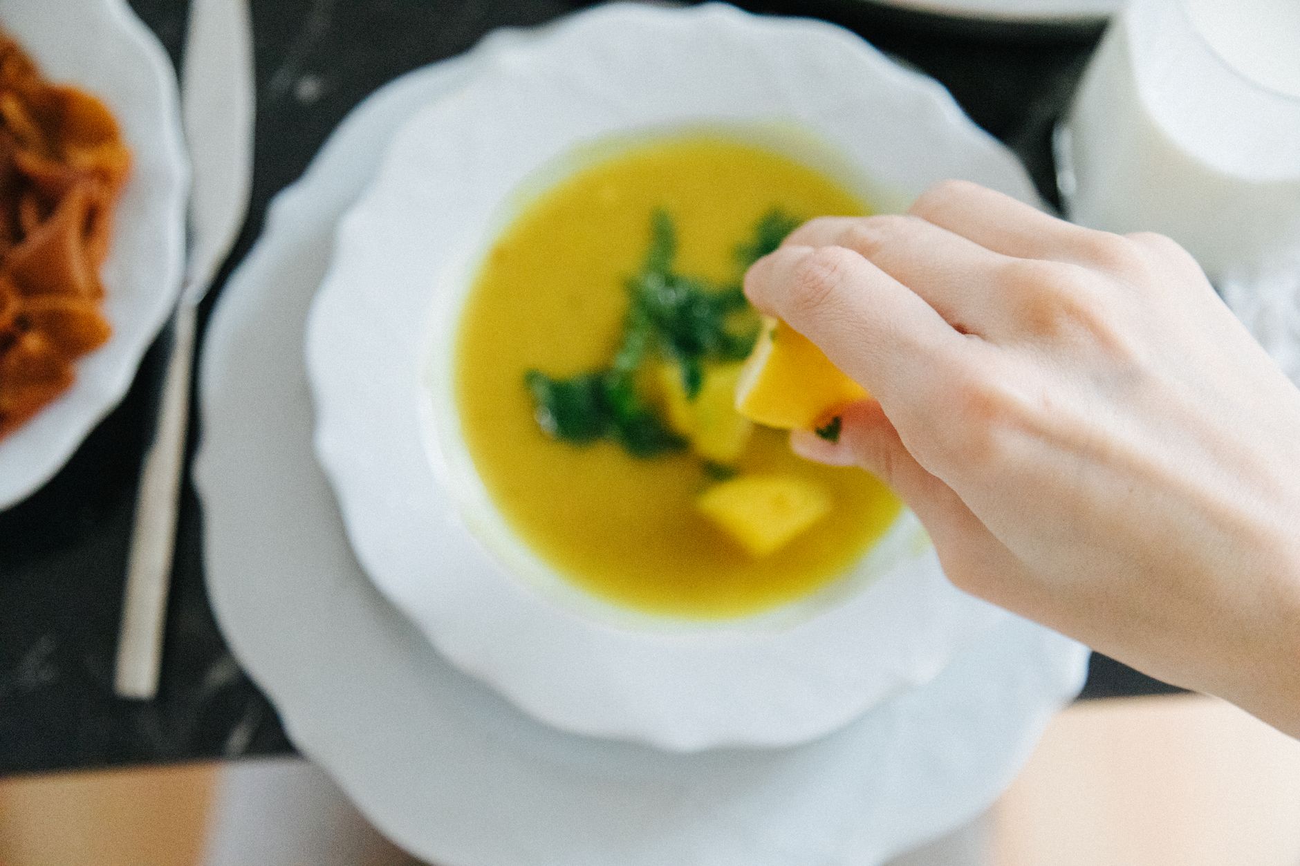 Ein Löffel Linsensuppe mit Zitrone und Petersilie, daneben ein zweiter Teller