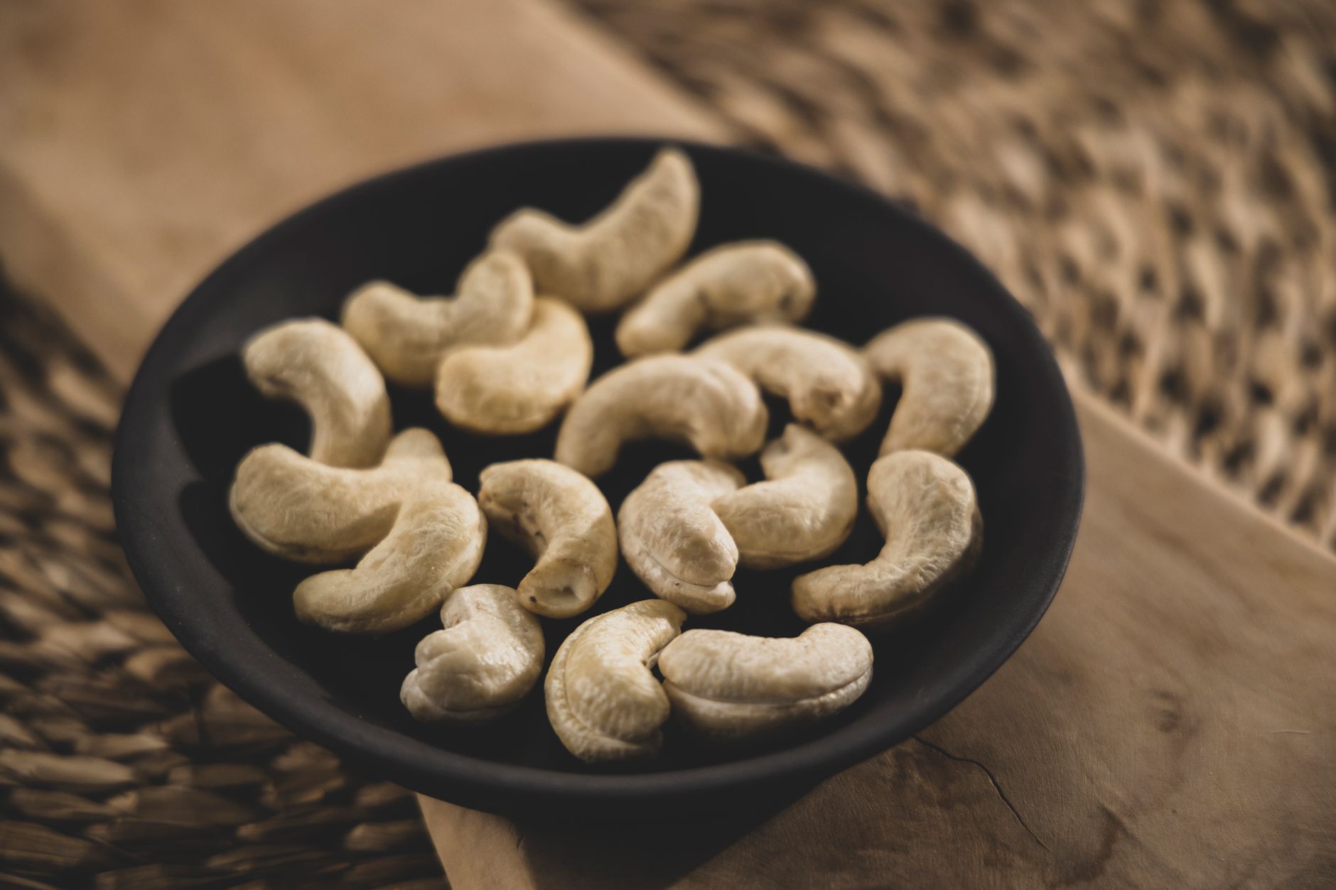 Cashewkerne in einer dunklen Schale auf einem Holzbrett